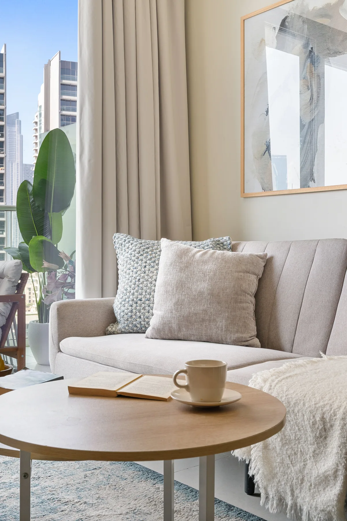 Una sala luminosa con sofá, mesa de centro y ventanas altas.