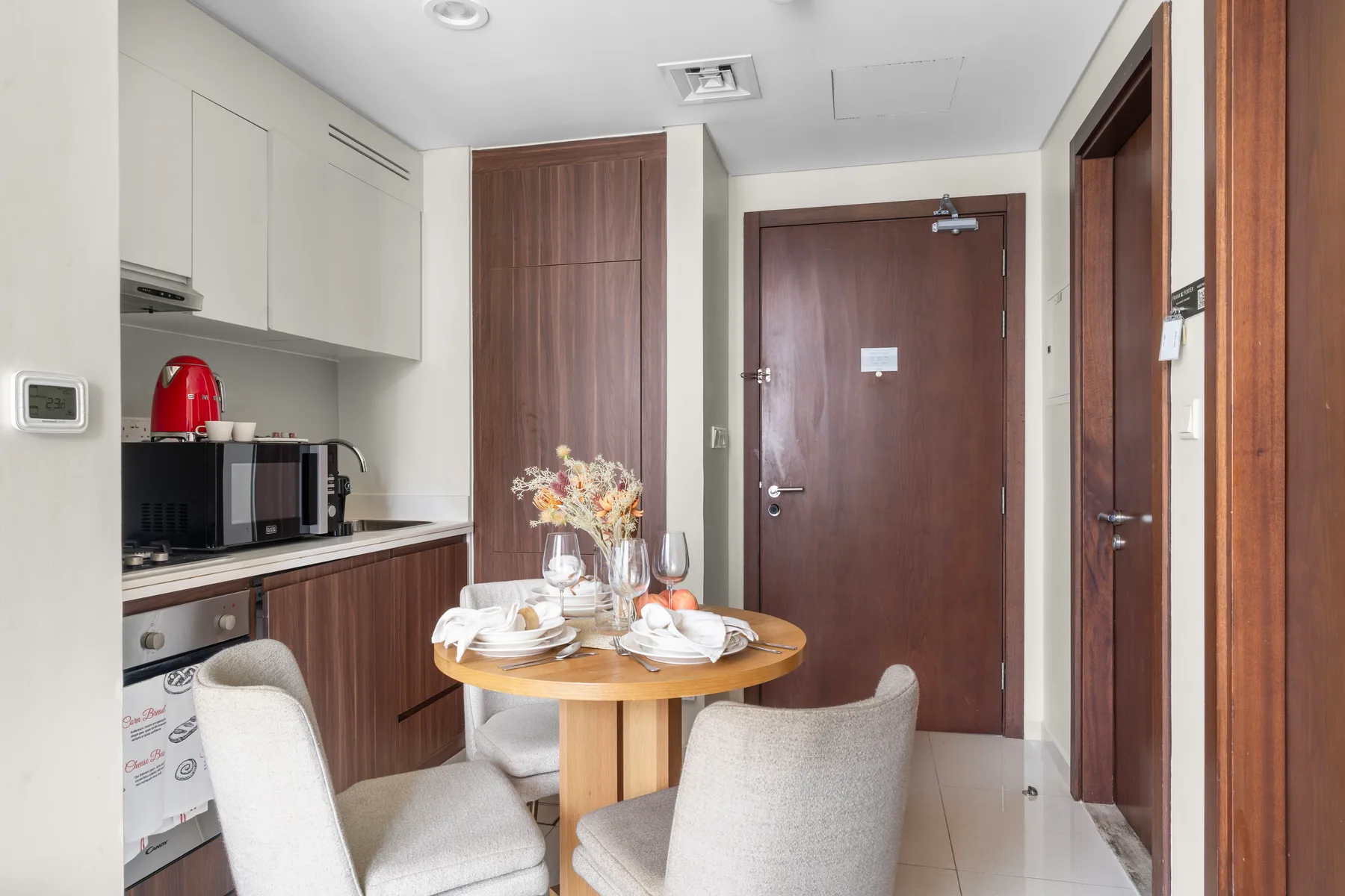 Comedor con una mesa redonda y sillas junto a una cocina compacta.
