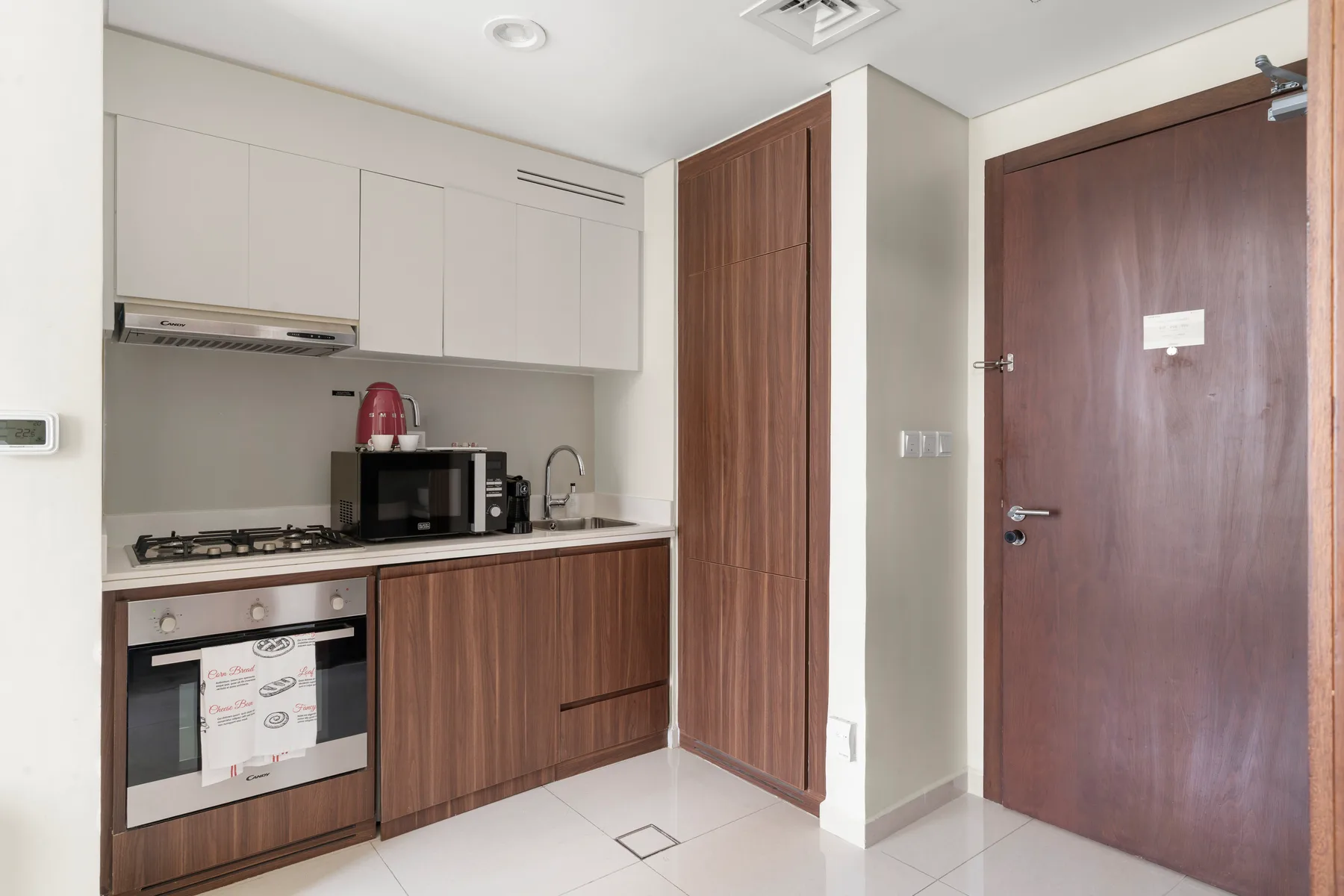Una cocina compacta con armarios, encimera y zona de cocción junto a una puerta de madera.
