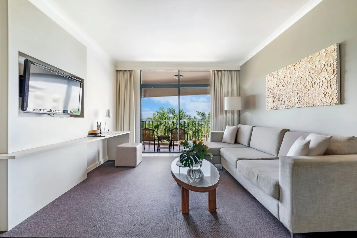 A living room with seating, a coffee table, and glass doors opening to a balcony.
