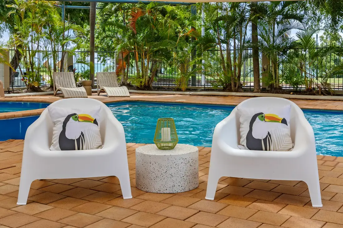Poolside seating with two white chairs and a small table beside the swimming pool.