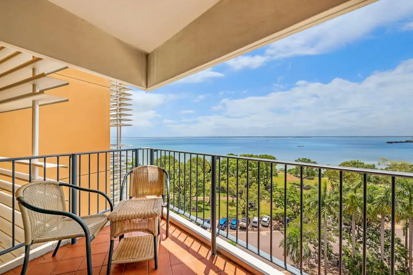 A furnished balcony overlooks the water and green coastal landscape.