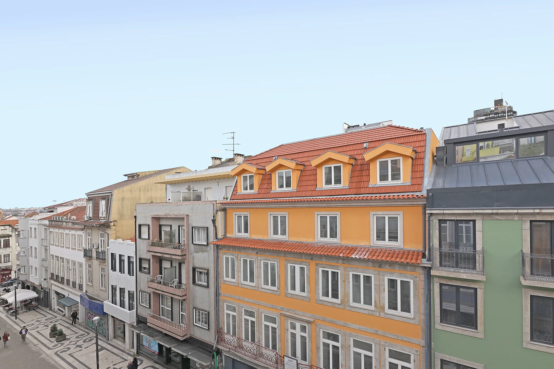 Una hilera de edificios urbanos con una fachada naranja y tejado de tejas.