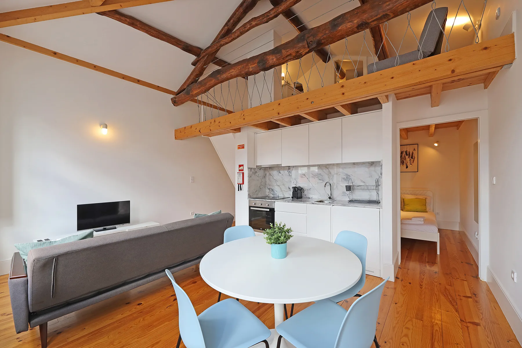 Un espacio tipo loft con comedor, mesa redonda y cocina.