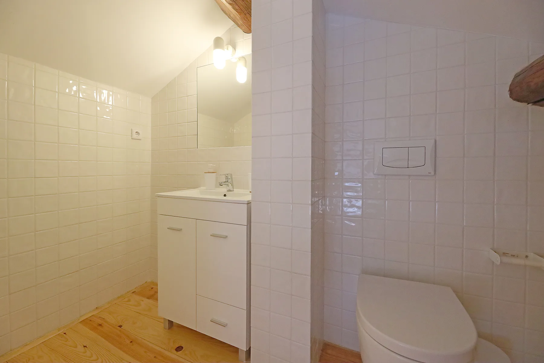 Un baño con azulejos, un lavabo con mueble y un inodoro.