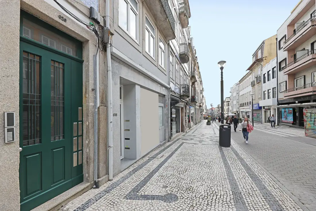 Una calle peatonal empedrada, bordeada de edificios y escaparates.