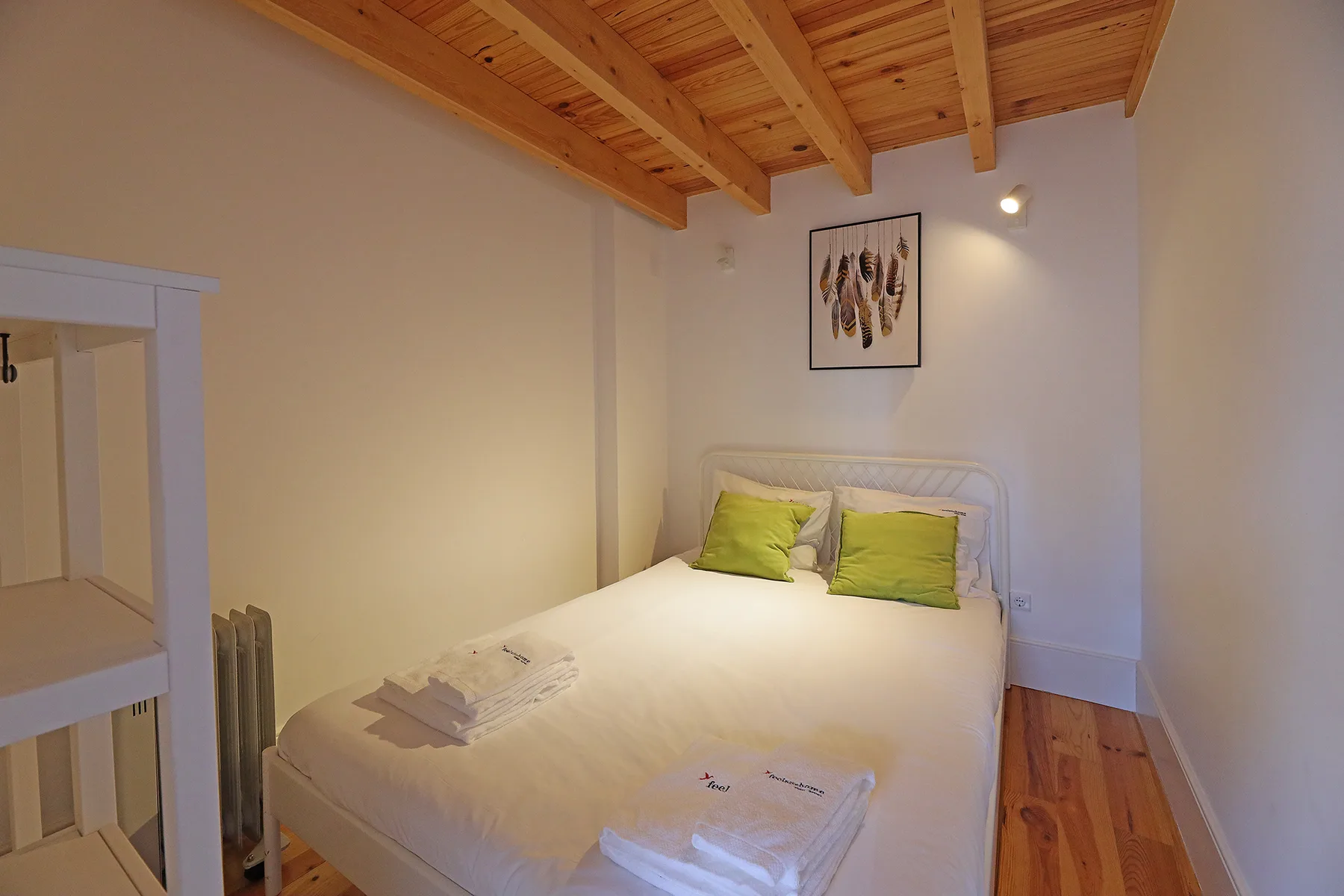 Un dormitorio con una cama doble, cojines verdes y un techo de madera.