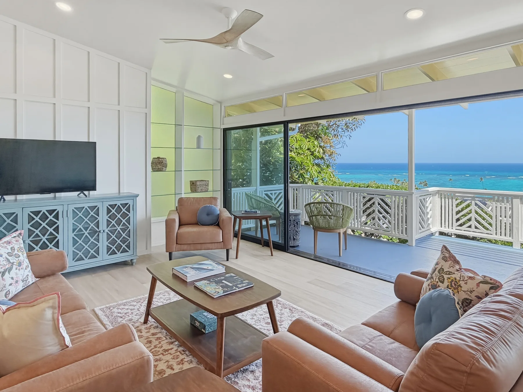 A bright living room with seating and large windows overlooking the ocean.