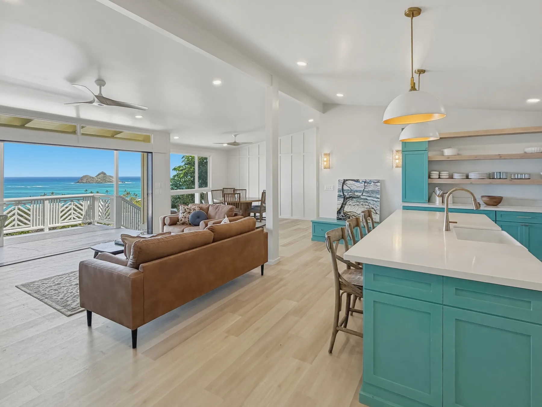An open-plan living room and kitchen with a brown sofa and turquoise island.