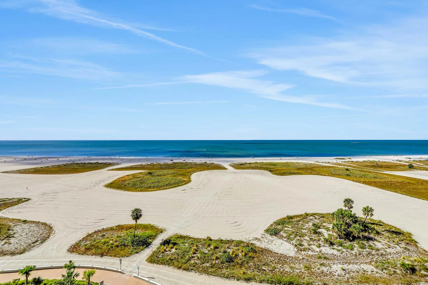 A sandy coastal landscape with low dunes and the ocean beyond.