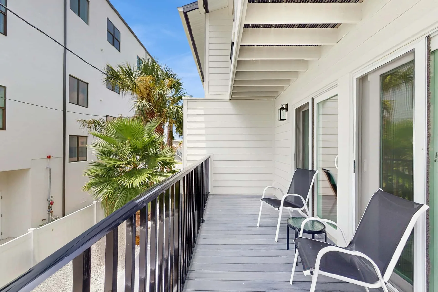 A covered outdoor balcony with seating and a black railing.