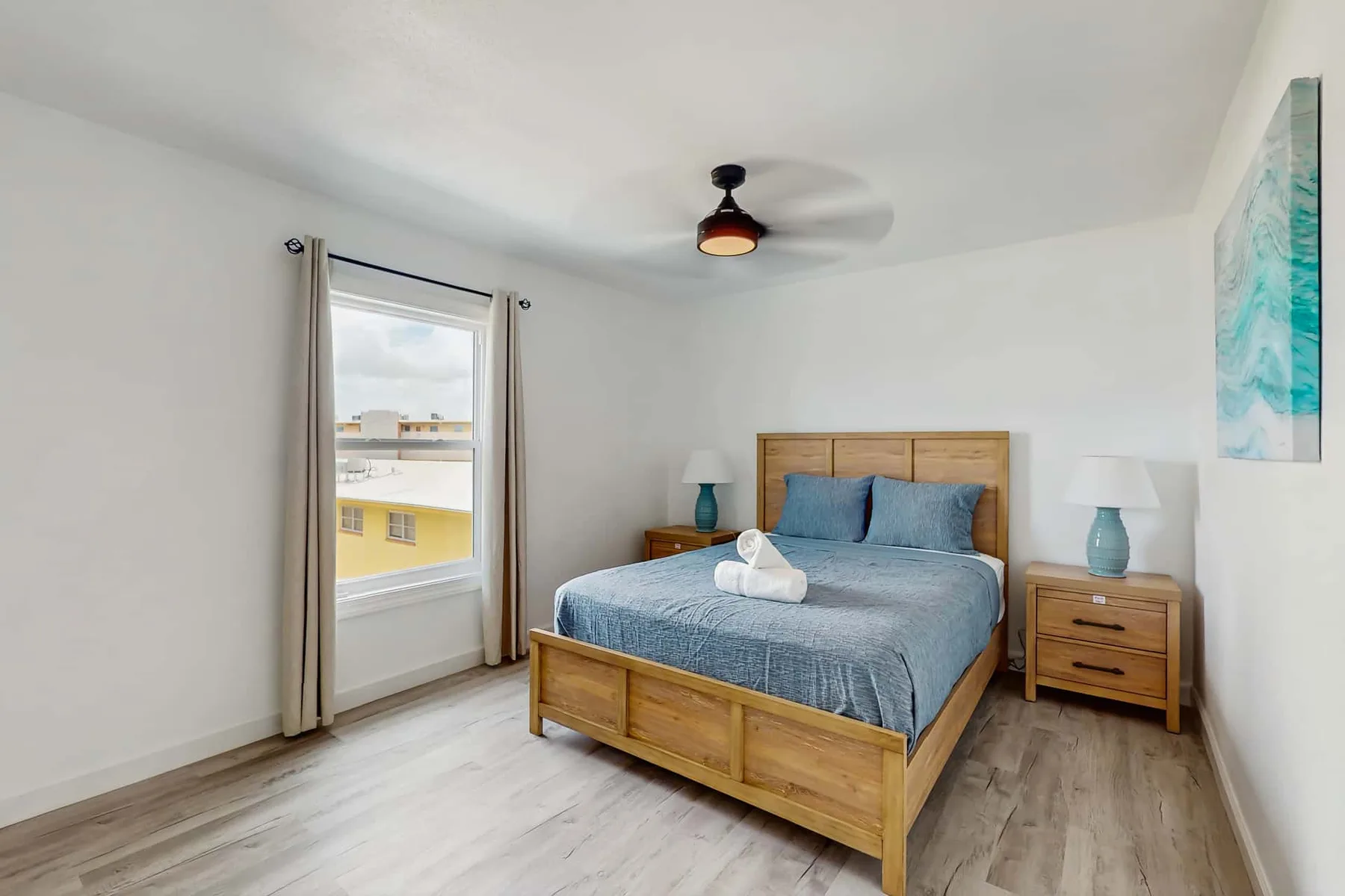 A bedroom with a wooden bed, blue bedding, and a window.