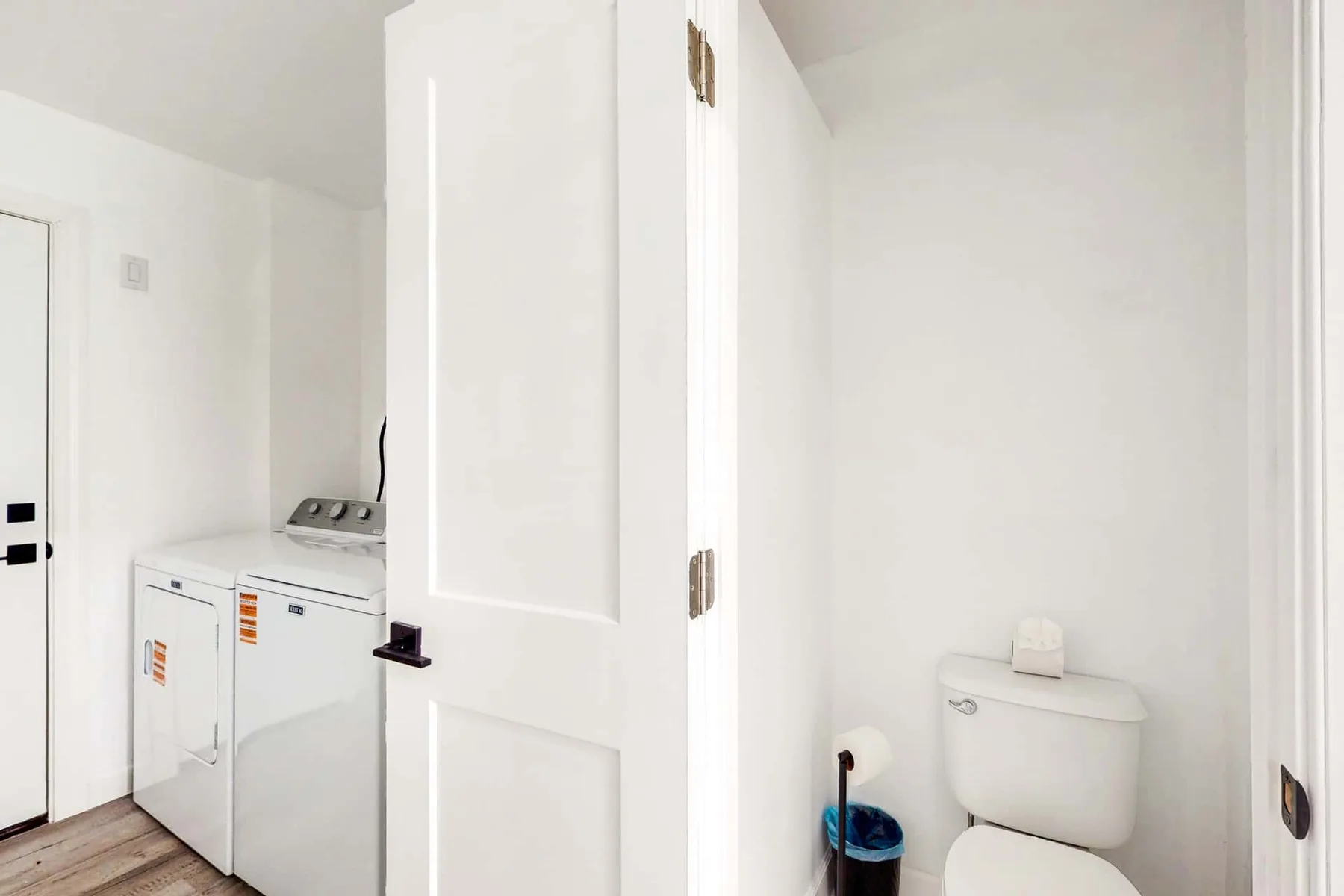 A small bathroom with a toilet beside a laundry machine.