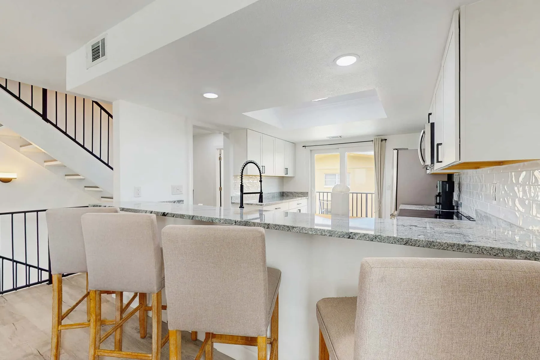 An open-plan kitchen with a breakfast bar and staircase.
