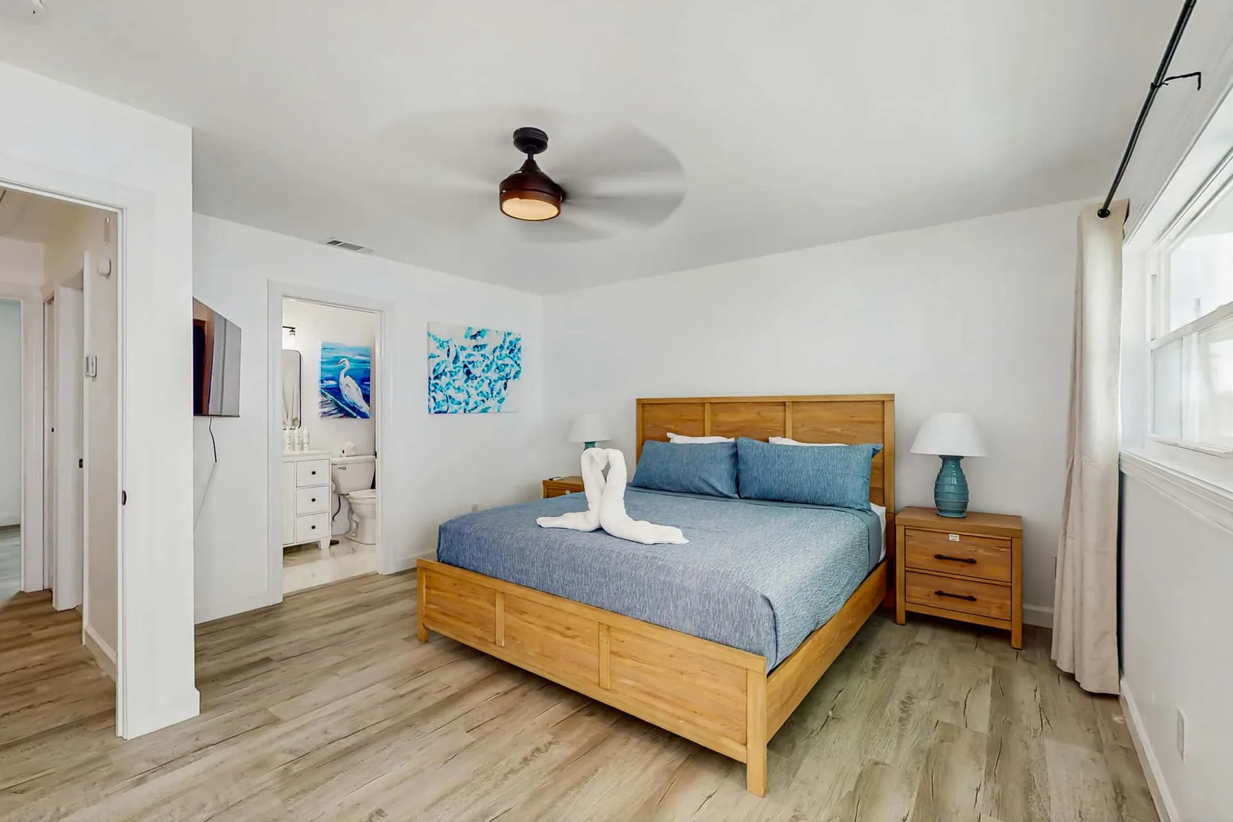 A bright bedroom with a wooden bed, blue bedding, and matching bedside tables.