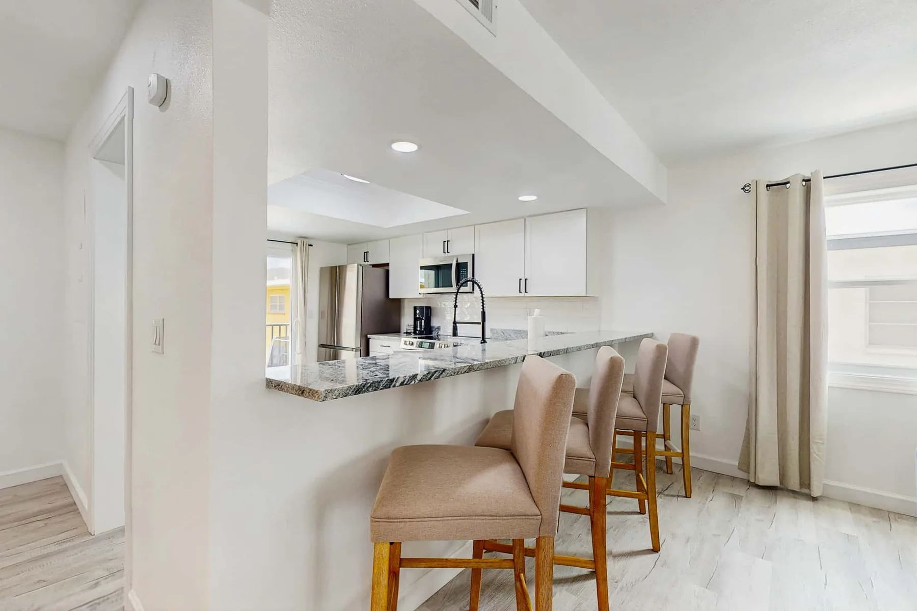 An open kitchen and dining area has a counter with upholstered seating.