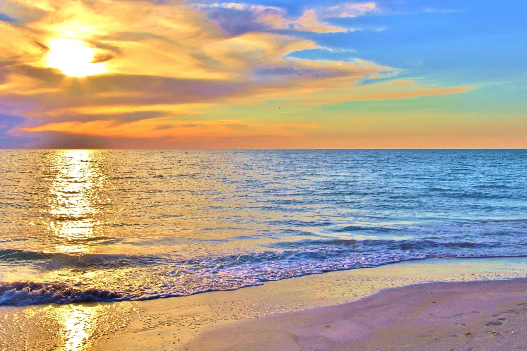 A beach at sunset, with gentle waves reaching the shore.
