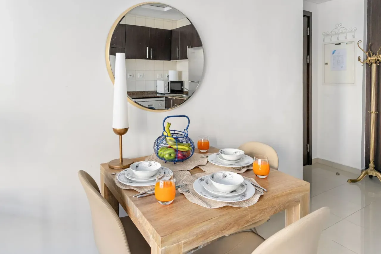 Una mesa de comedor está puesta con platos y bebidas en un comedor luminoso.