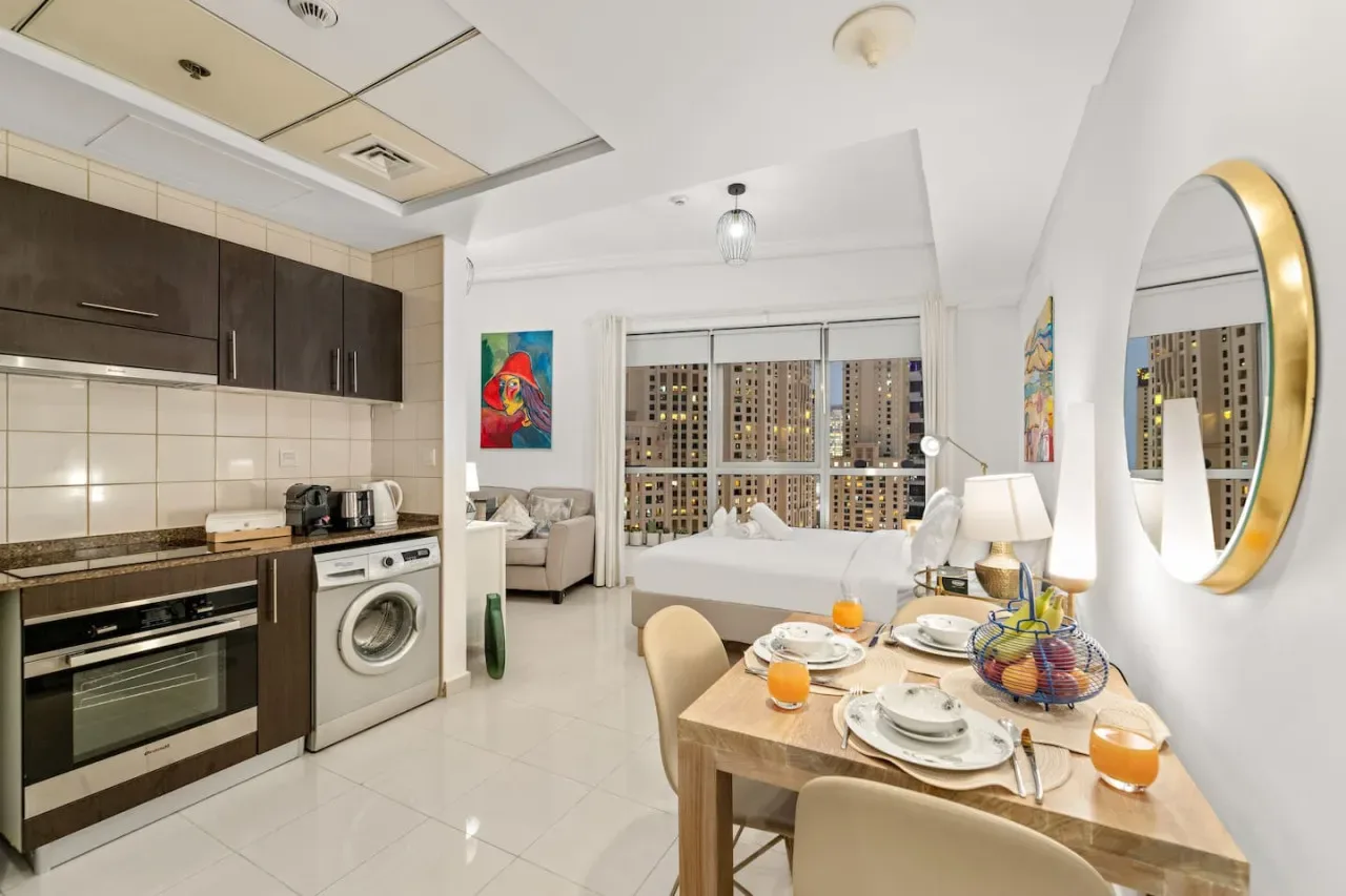 Una cocina abierta al comedor, con una mesa puesta junto a grandes ventanas.