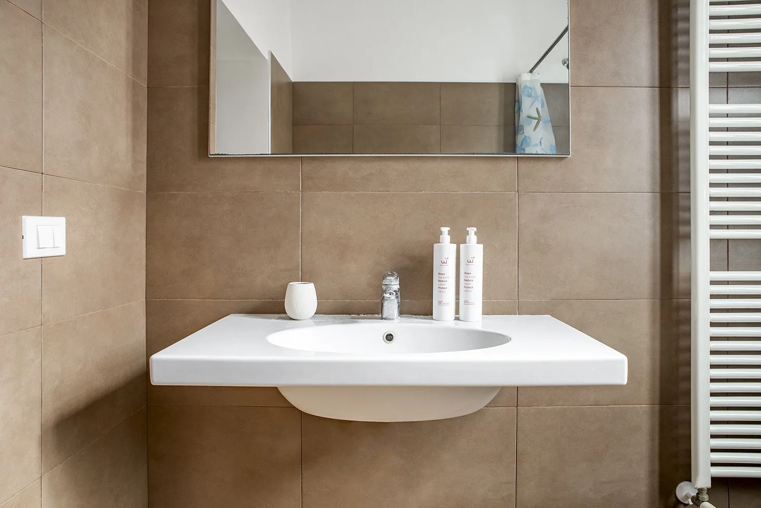 Un lavabo de baño blanco bajo un espejo de pared.
