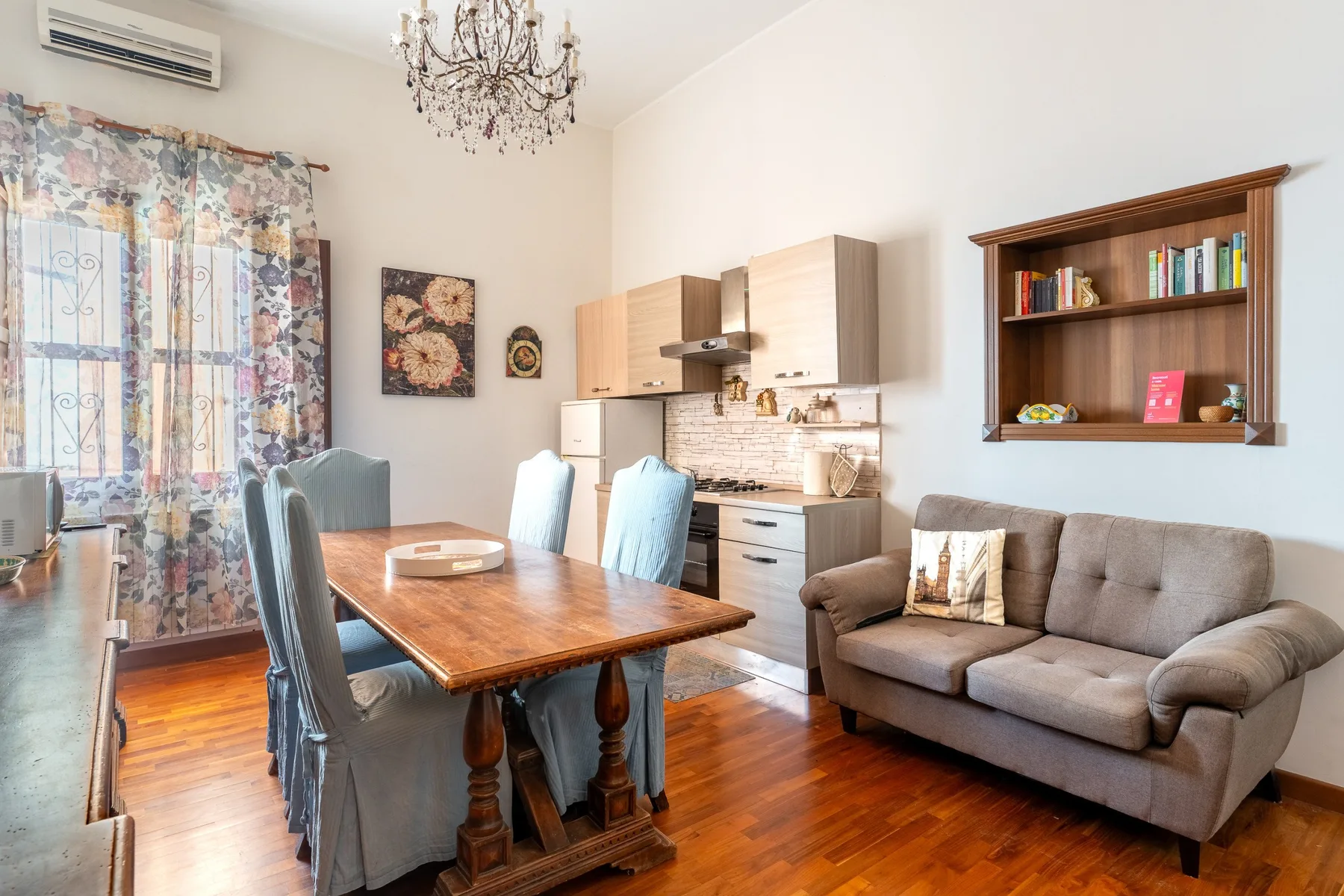 Comedor y sala de estar con una mesa de madera, armarios de cocina y asientos.