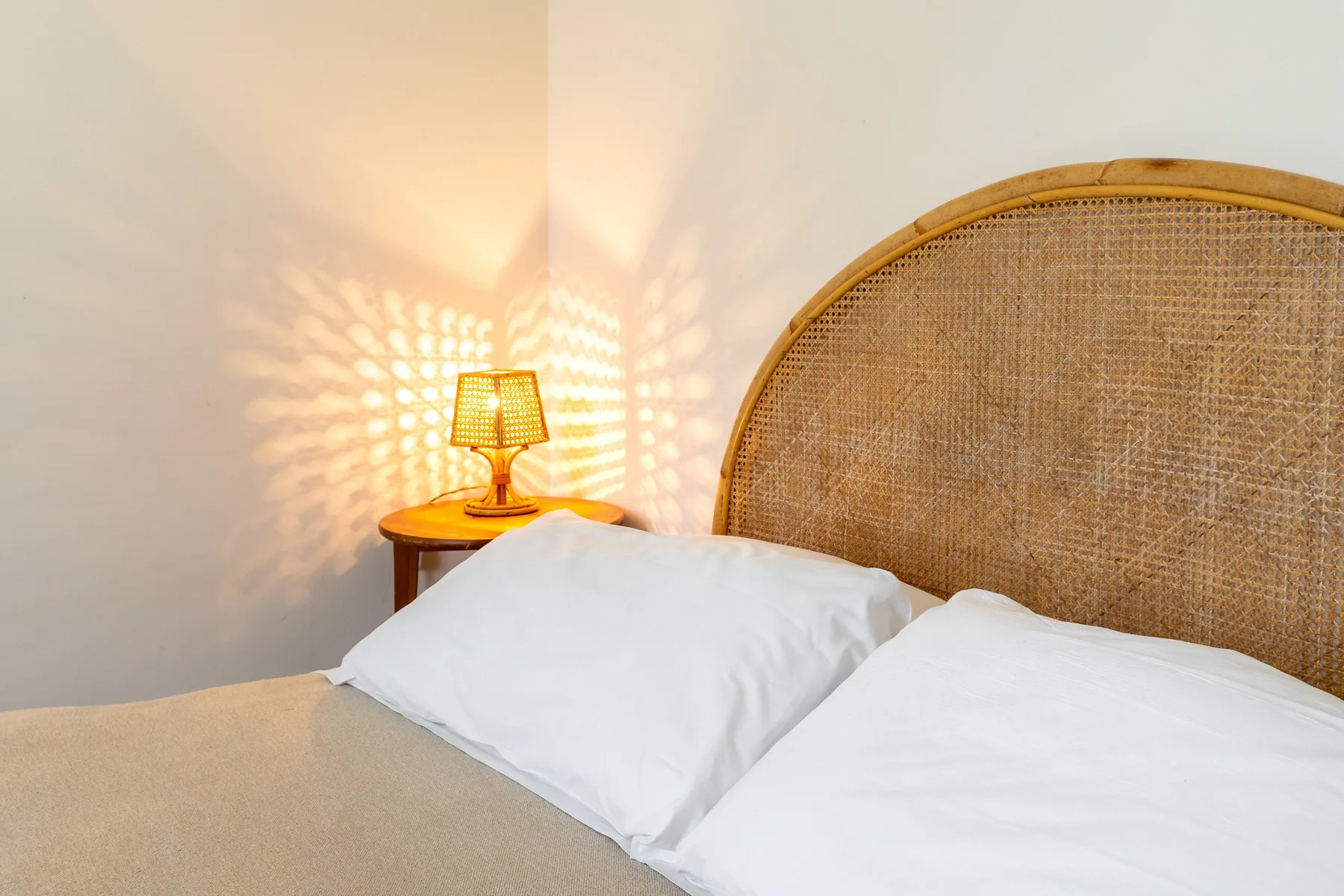 Un dormitorio con ropa de cama blanca y una lámpara de noche encendida.