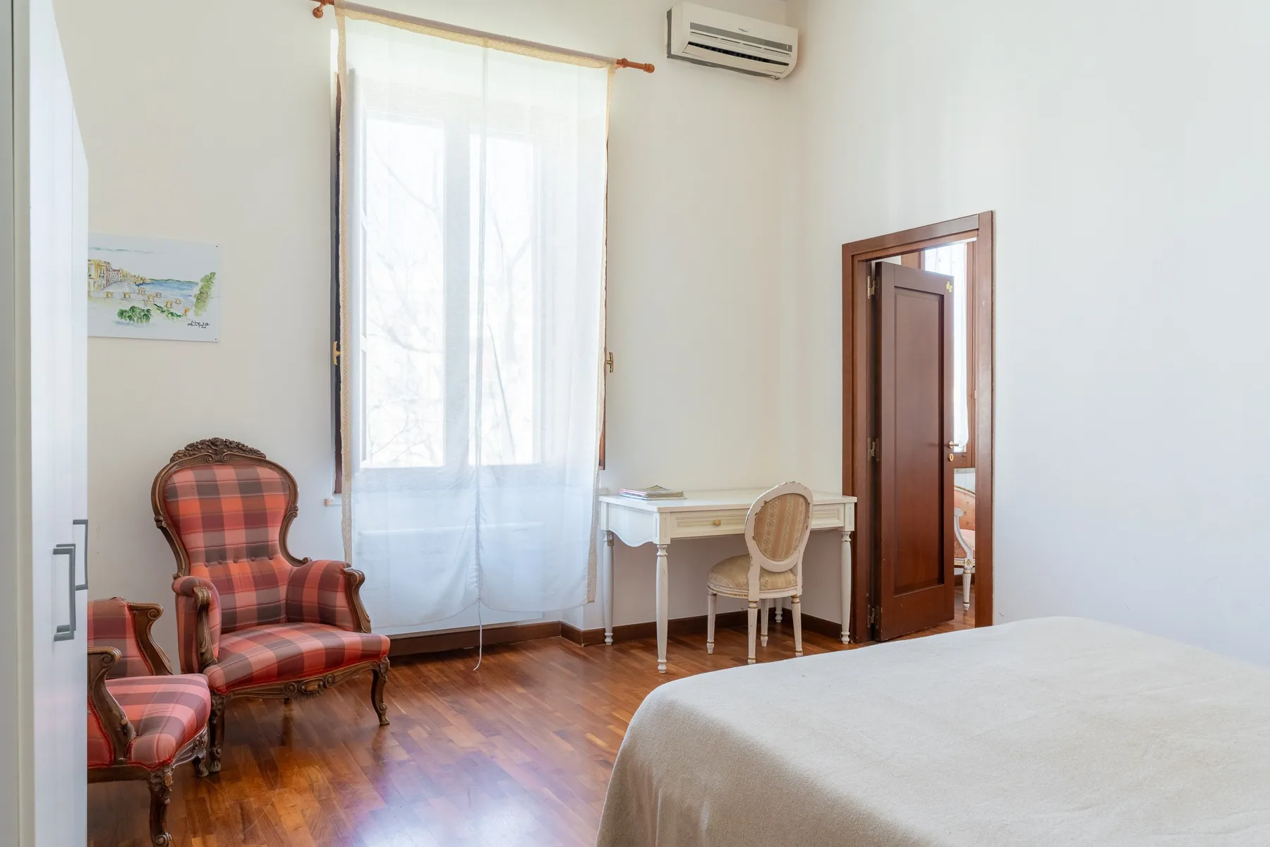 Un dormitorio con una cama, una ventana y un pequeño escritorio con asientos.