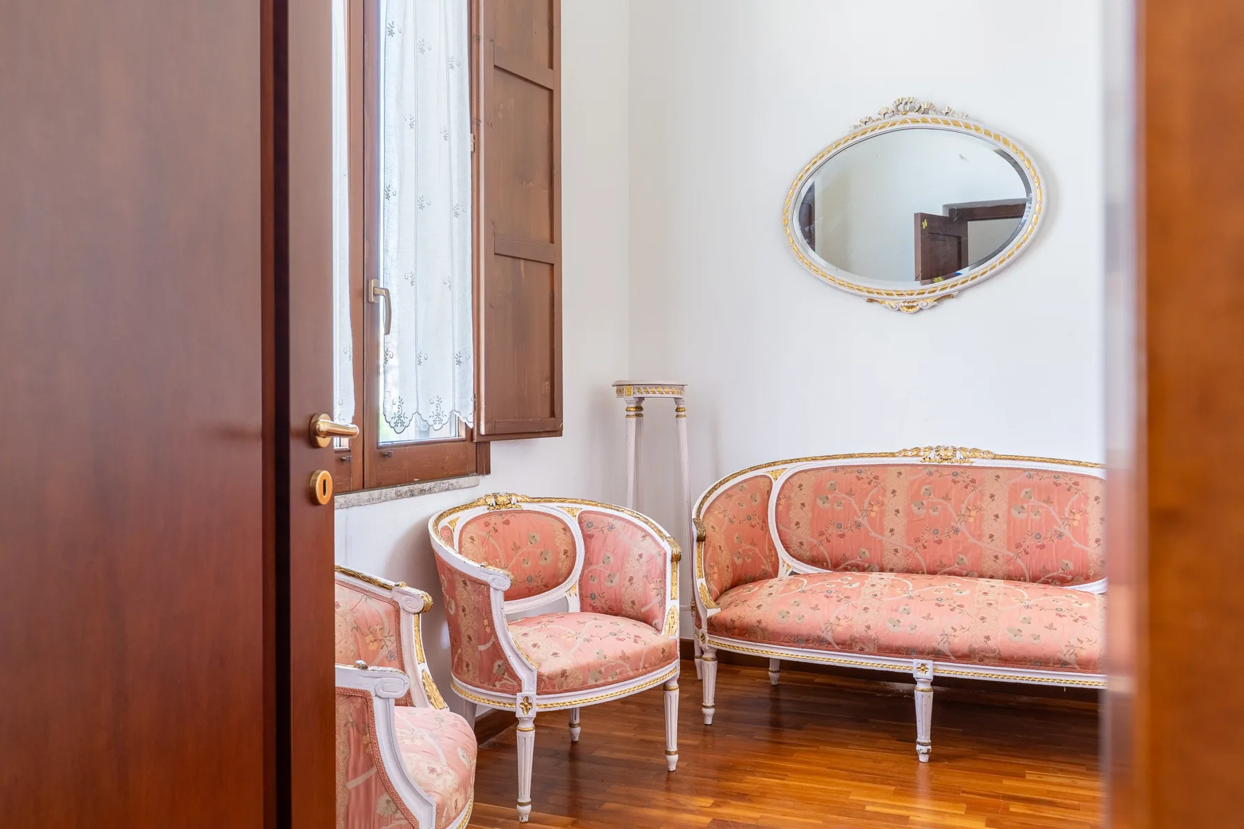 Una sala de estar con asientos tapizados junto a una ventana abierta.