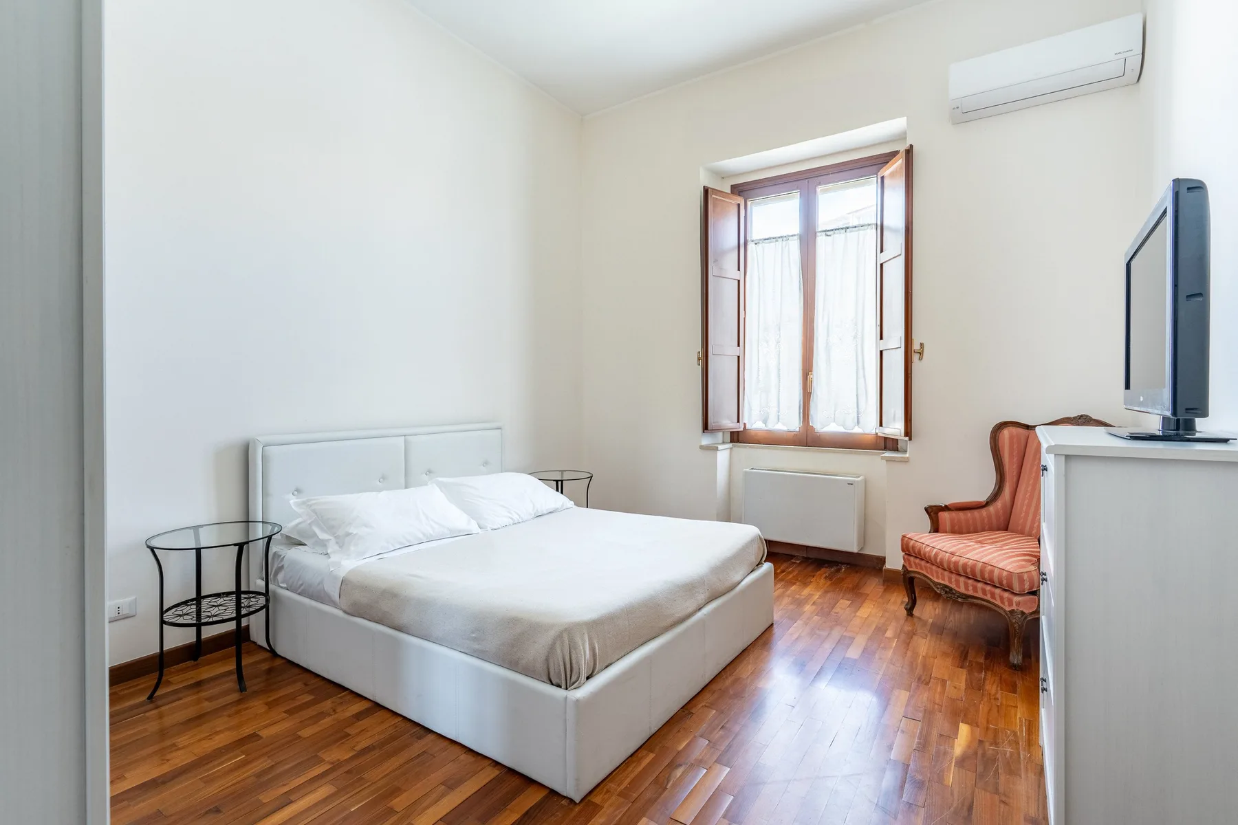 Un dormitorio con una cama, una ventana y un televisor.