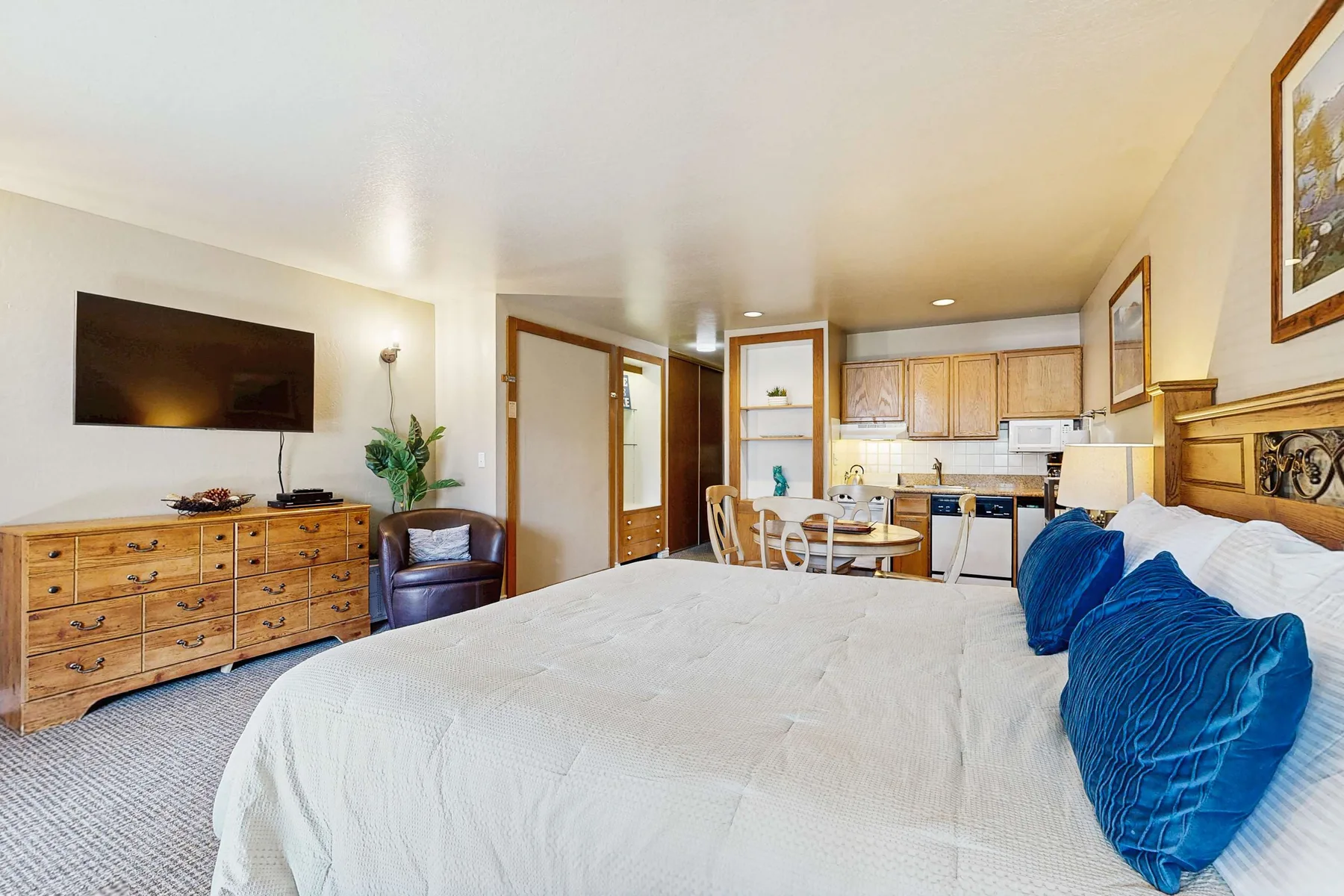 Dormitorio con una cama grande y una pequeña cocina al fondo.