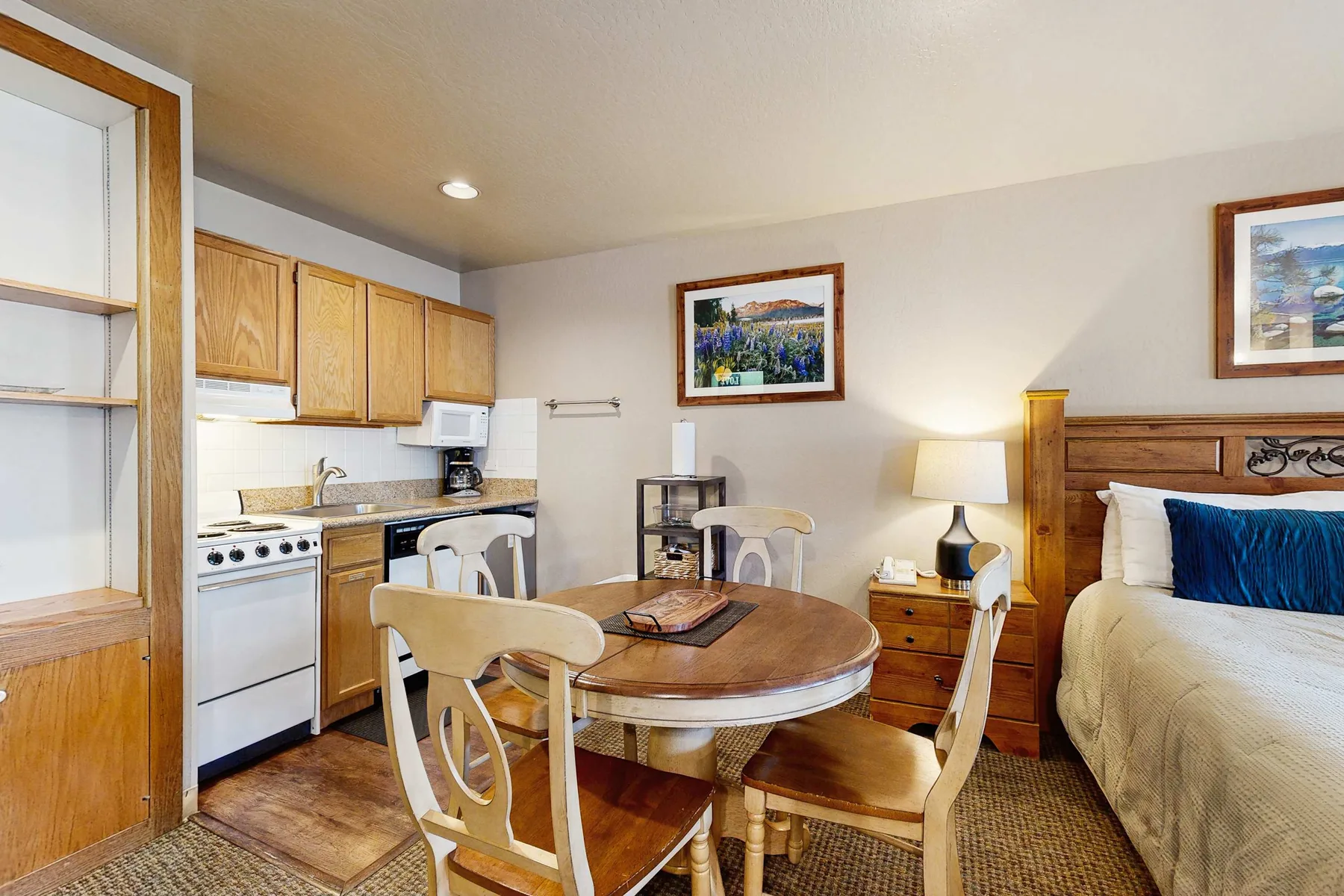 Una zona combinada de cocina y comedor con una cama junto a la mesa.