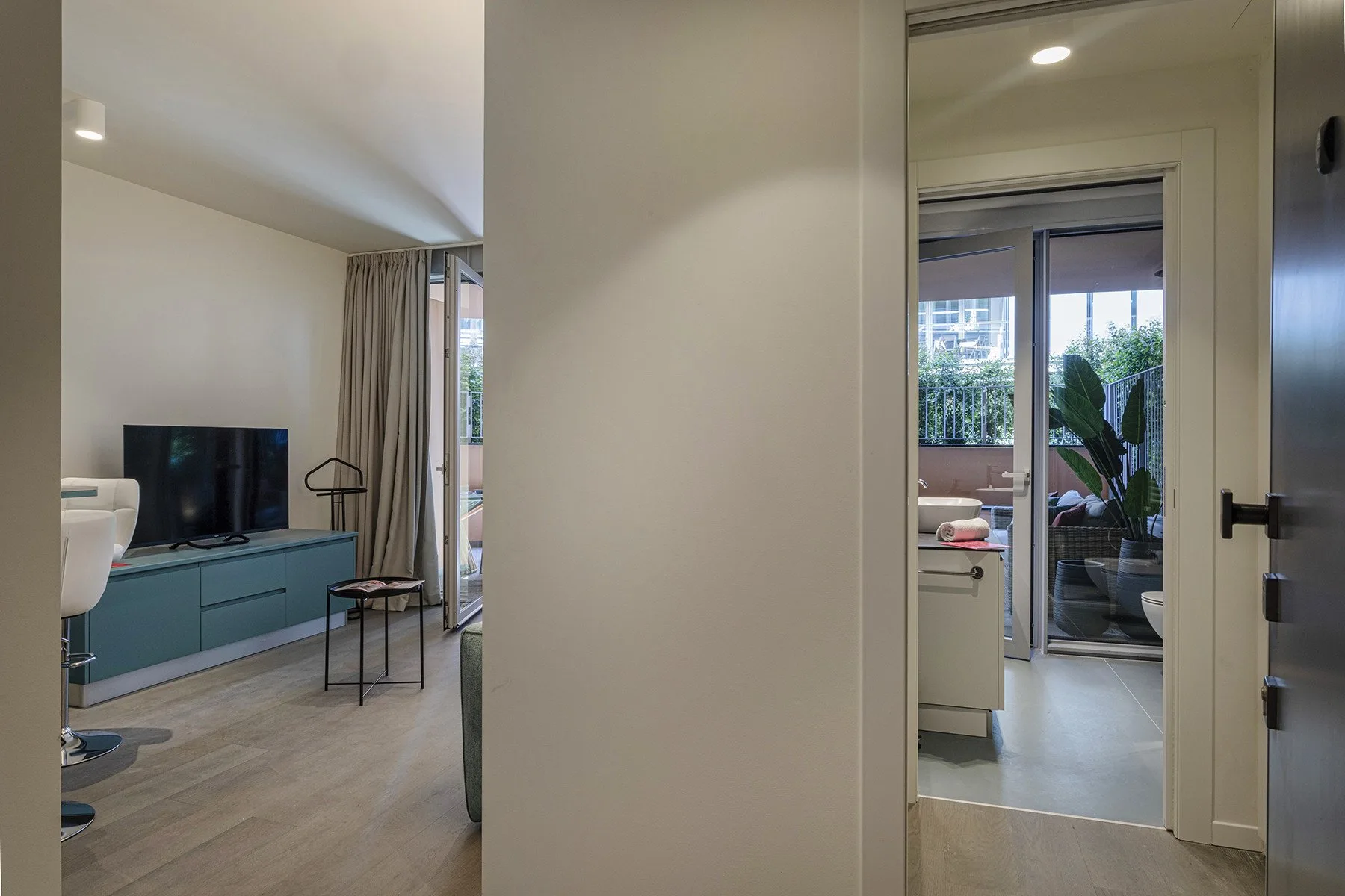 A living room with a television and seating beside a doorway to a bright patio.