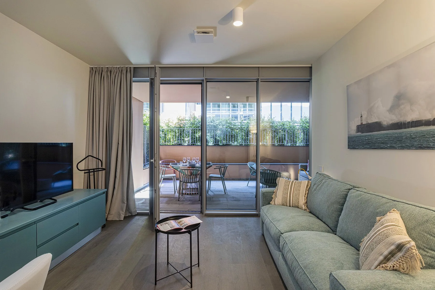 A living room with seating beside glass doors opening onto a furnished balcony.