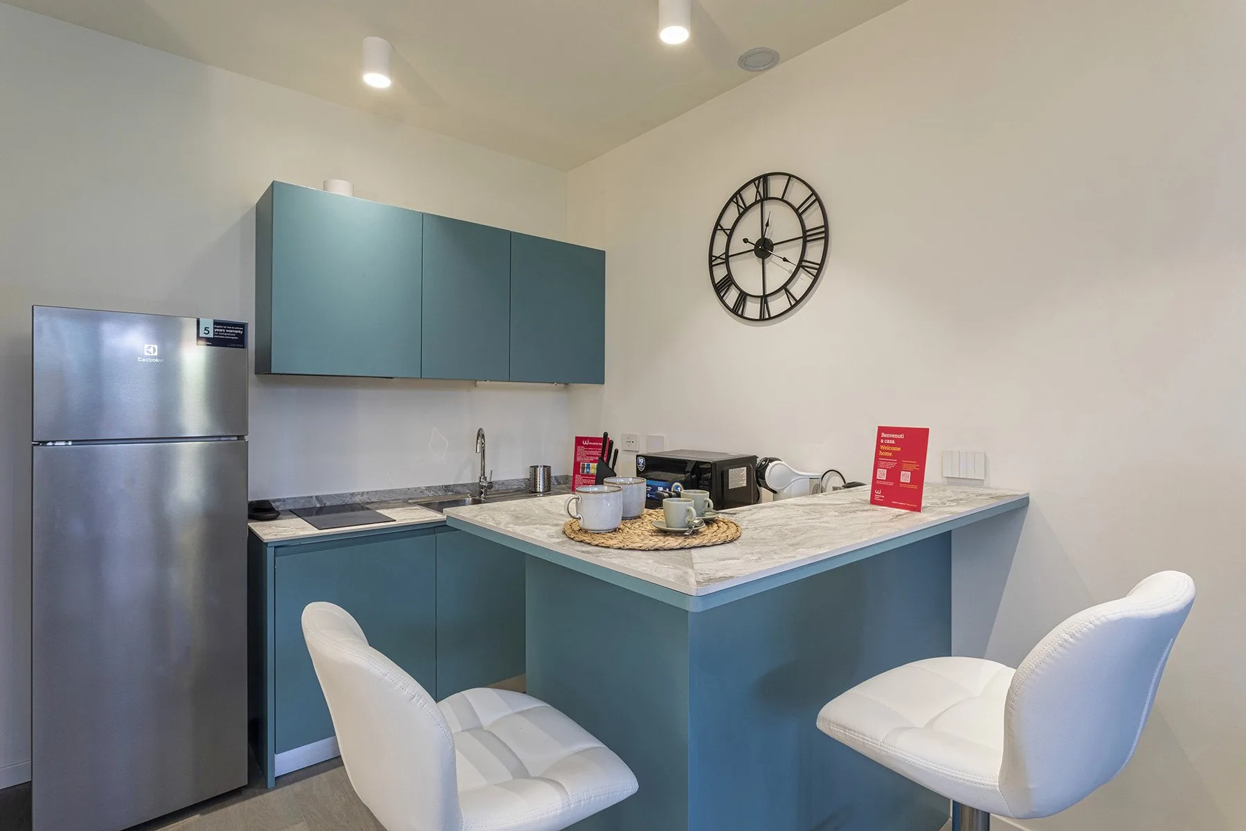 A modern kitchen with blue cabinets, a counter, and white seating.
