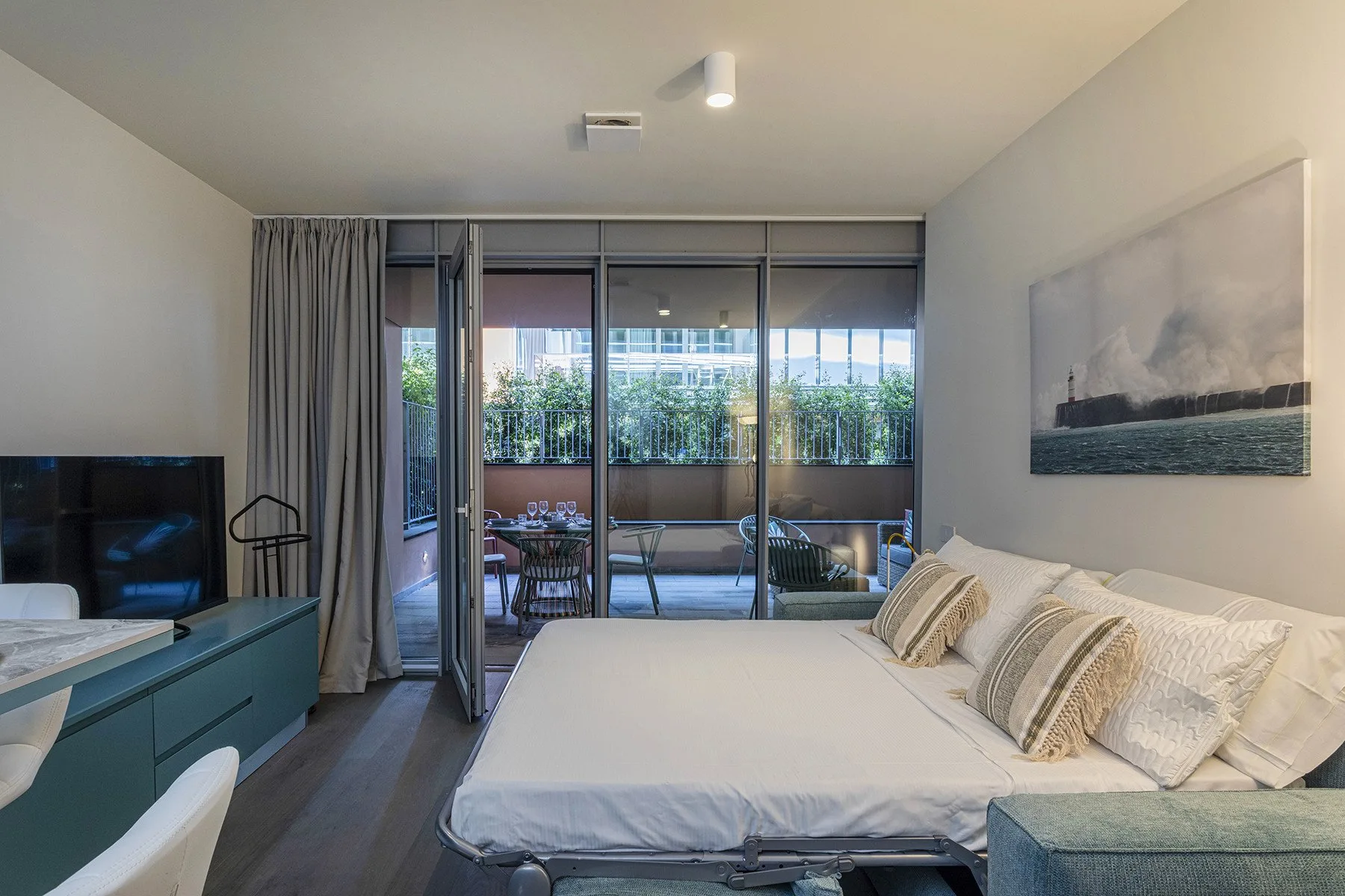 A bedroom with a large bed facing sliding glass doors and a balcony.
