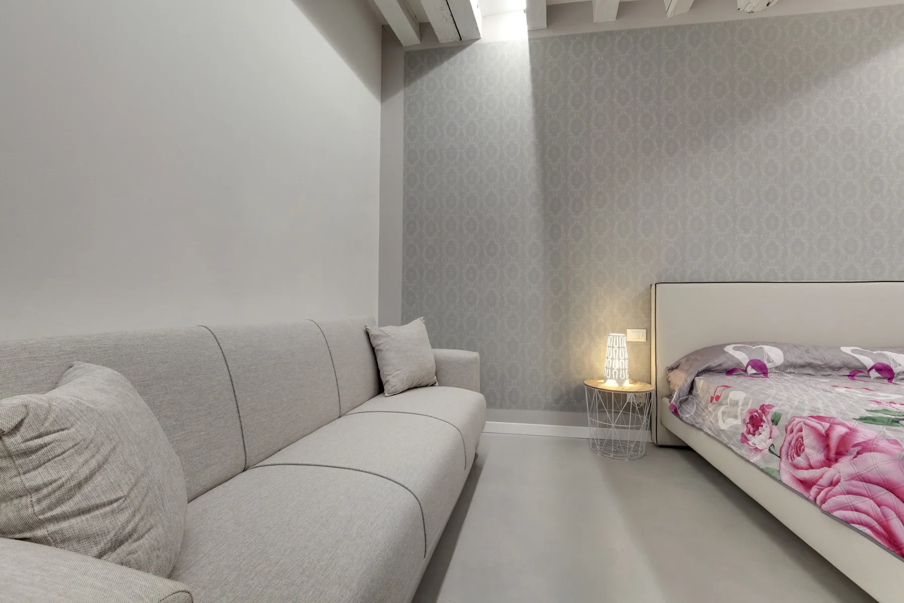 A bedroom with a bed and a gray sofa.