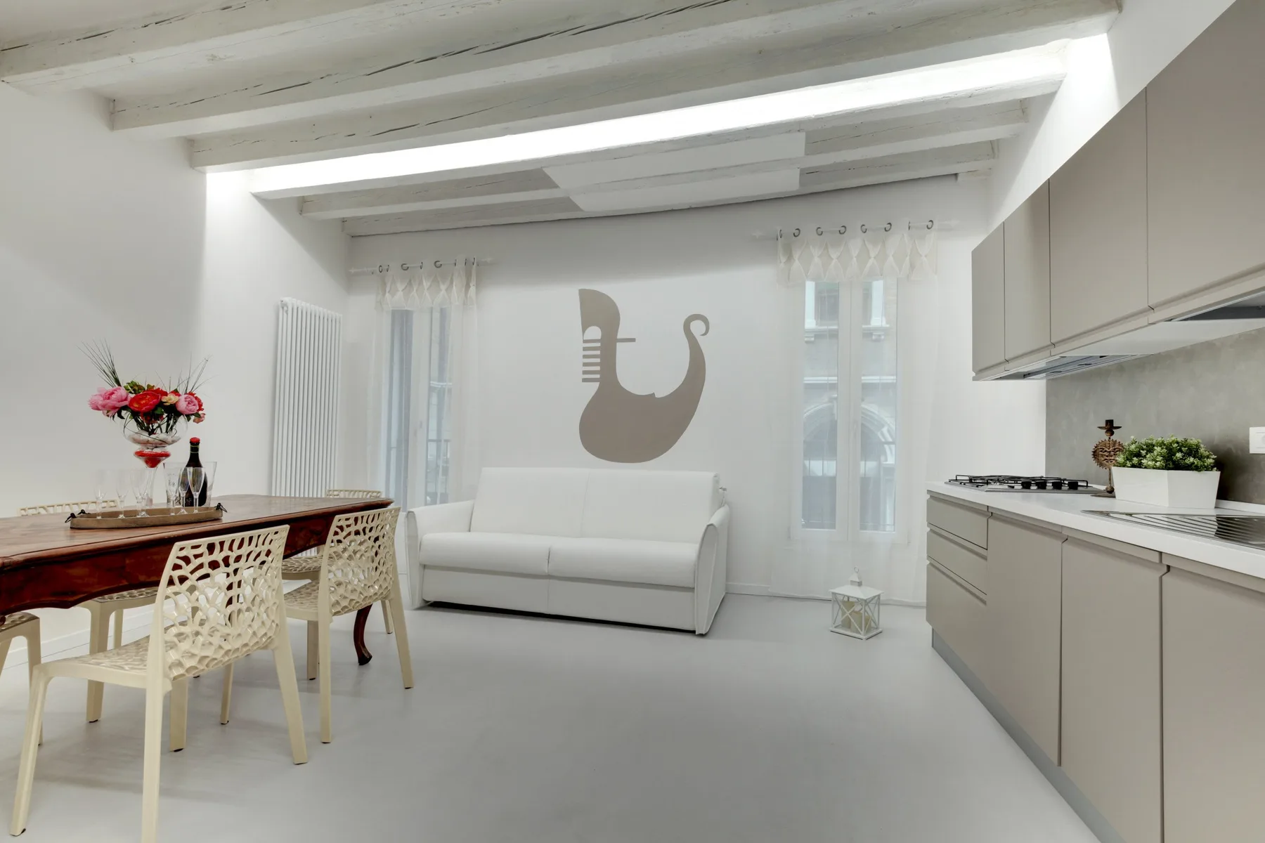 A bright open-plan room combines a dining area, living space, and kitchen.