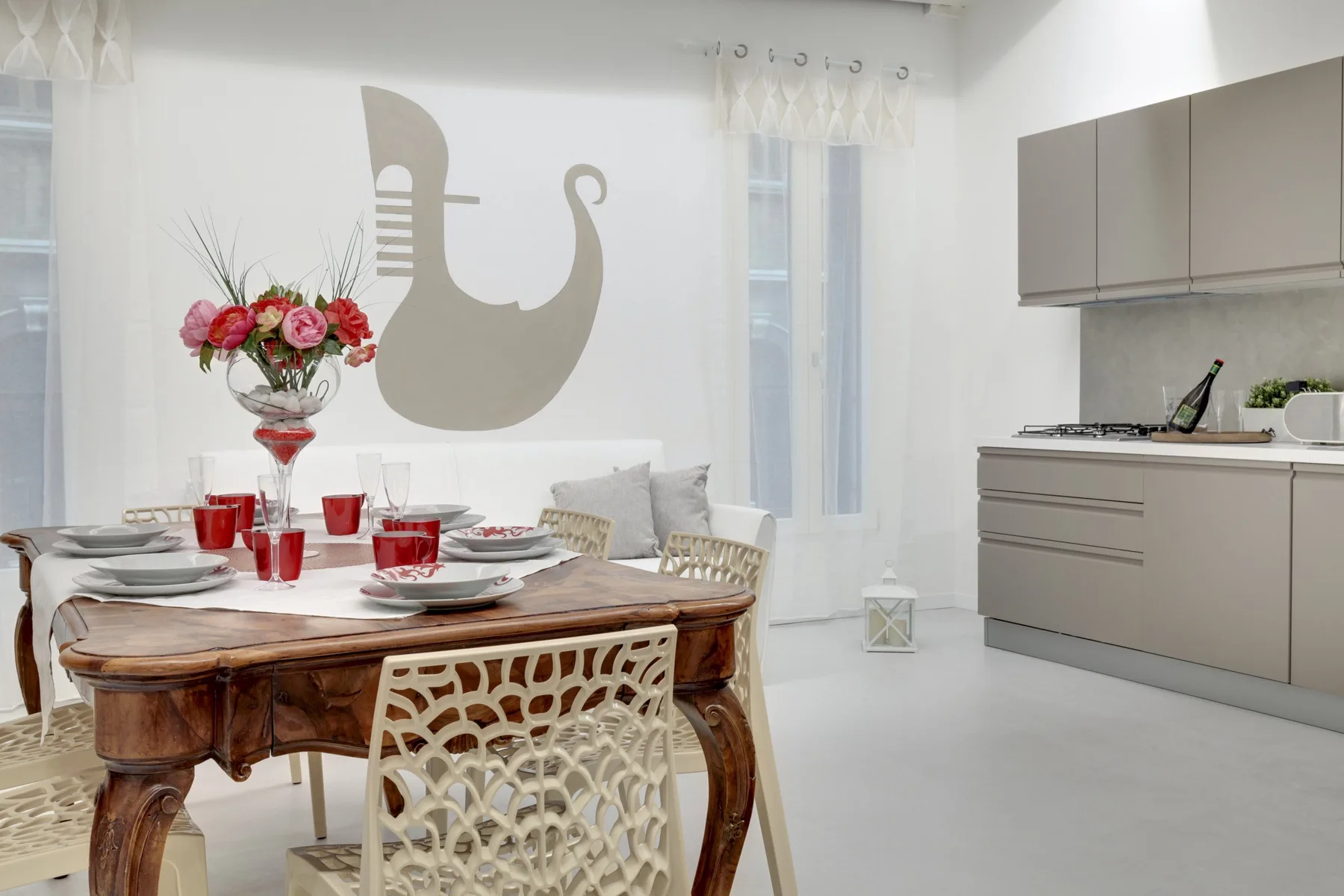 A dining area with a set table and a kitchen along the wall.