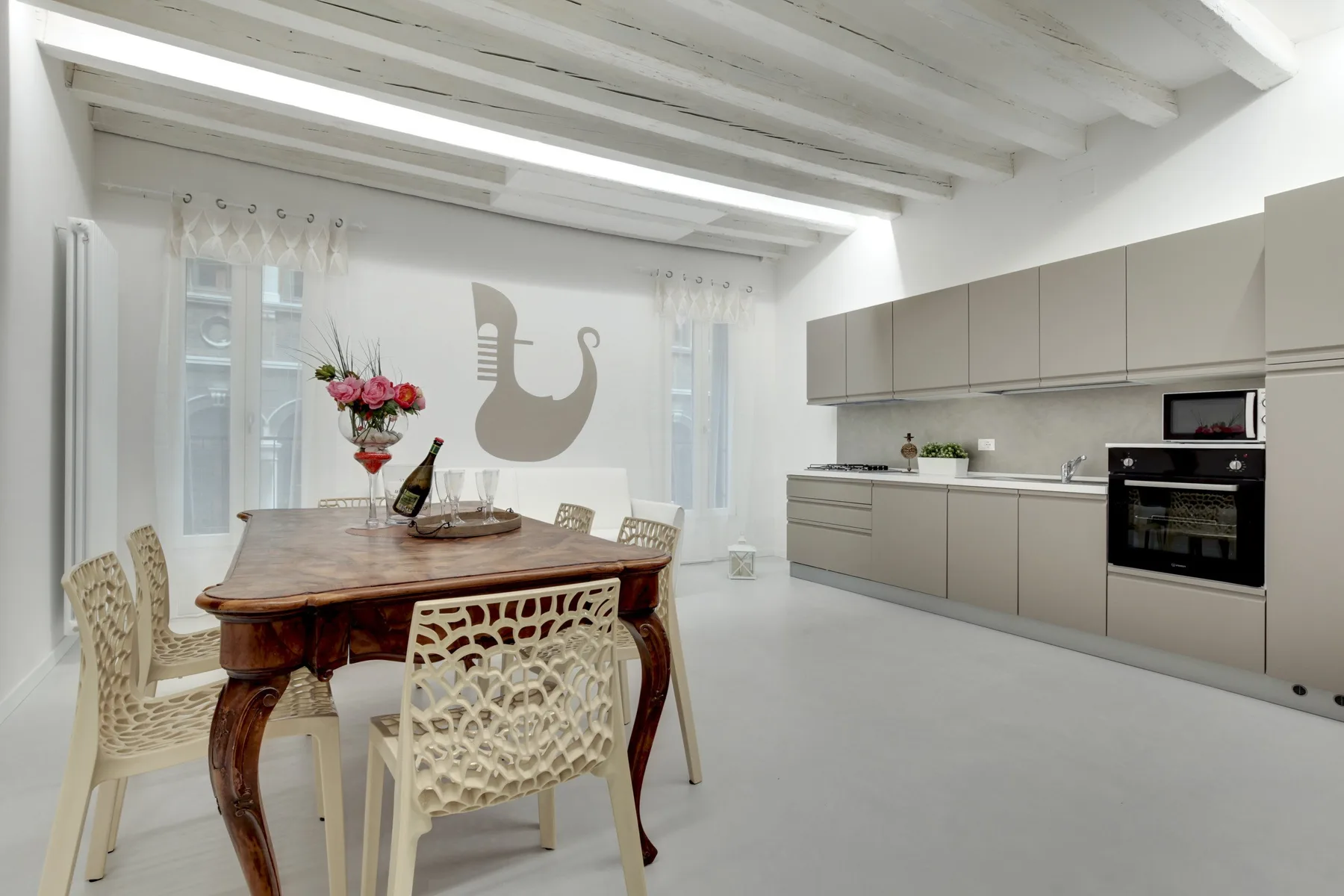 A bright dining area with a wooden table beside a modern kitchen.