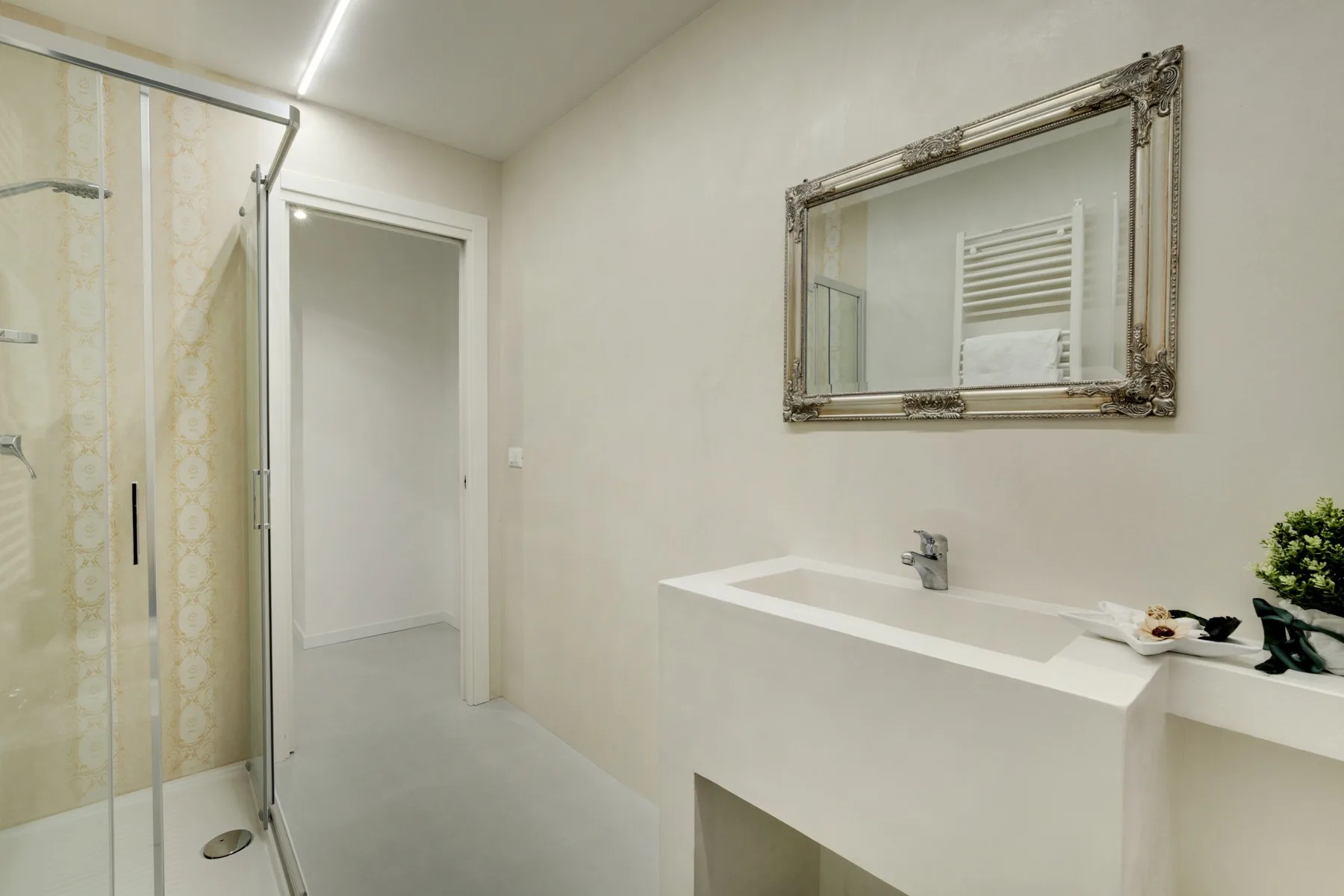 A bright bathroom with a walk-in shower and a wide white sink.