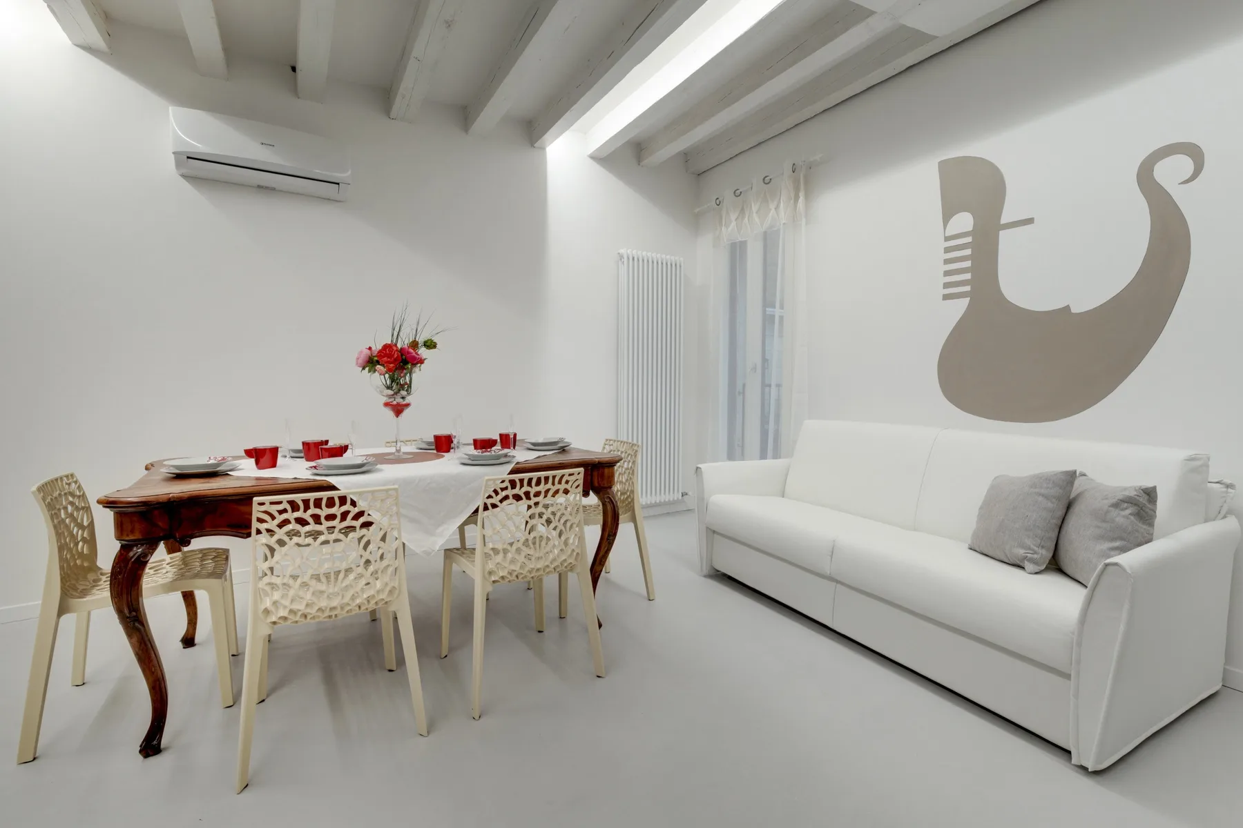 A bright dining and living area with a set table and white seating.