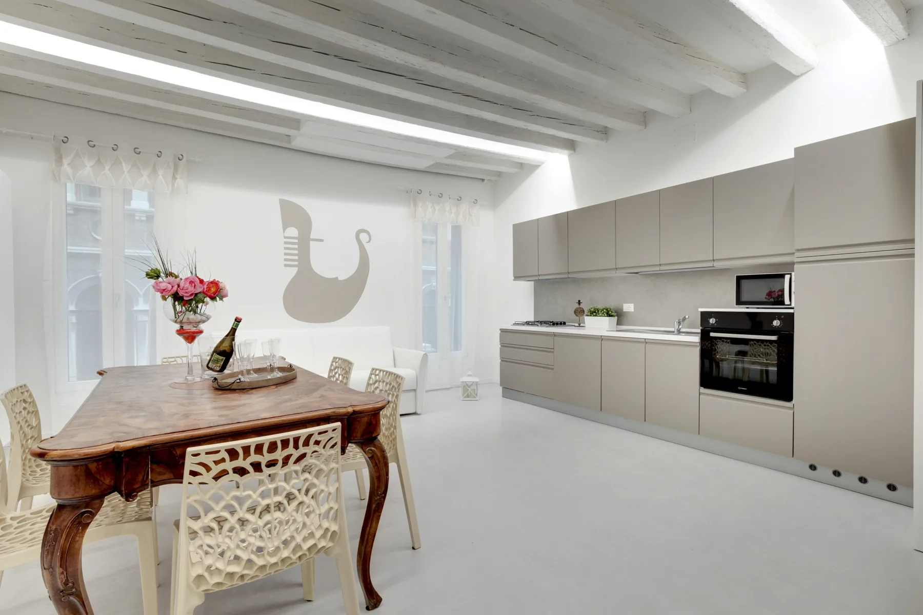 A bright kitchen and dining area with a wooden table and built-in appliances.