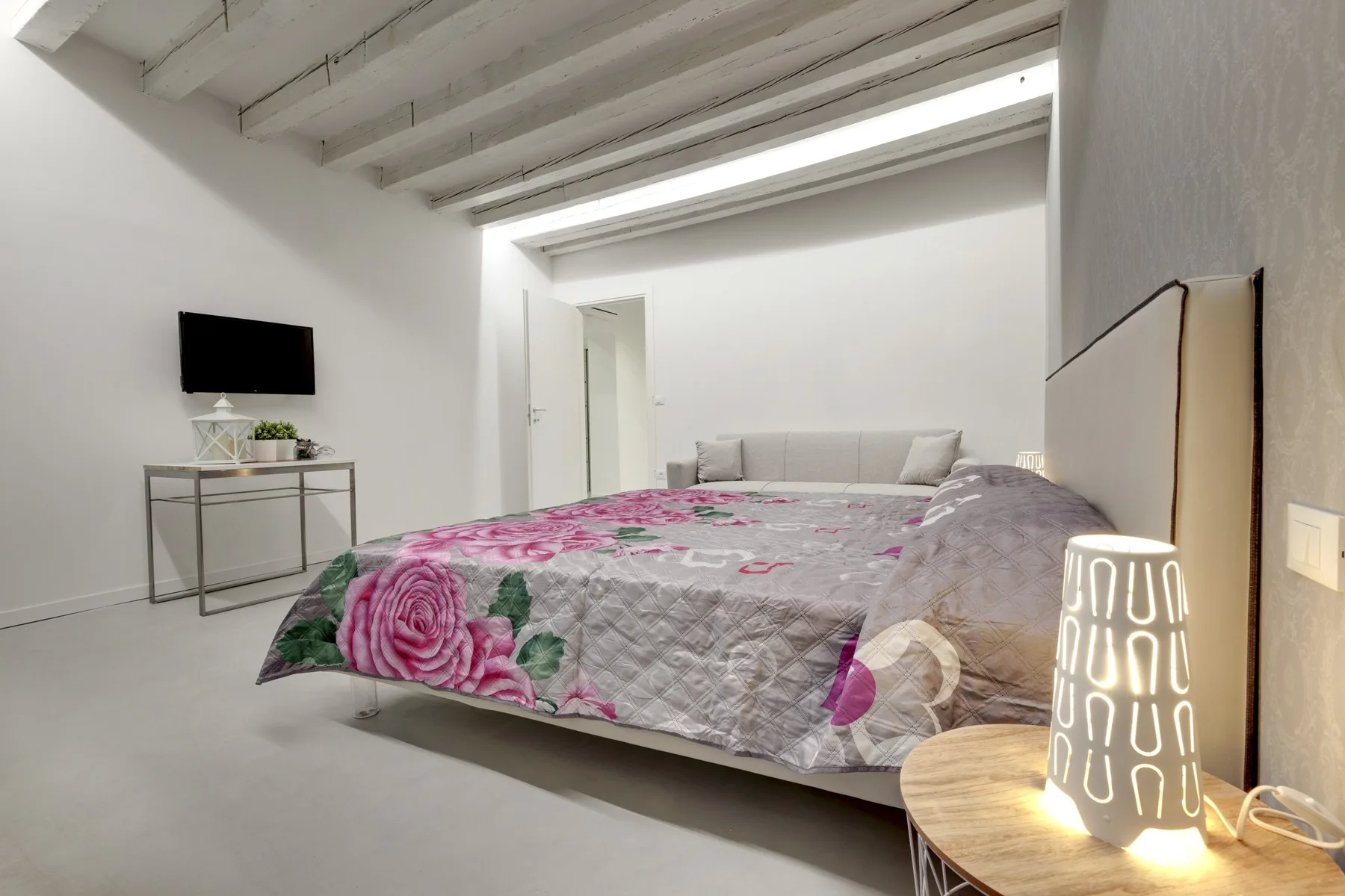 A bedroom with a bed covered in a floral-patterned bedspread.