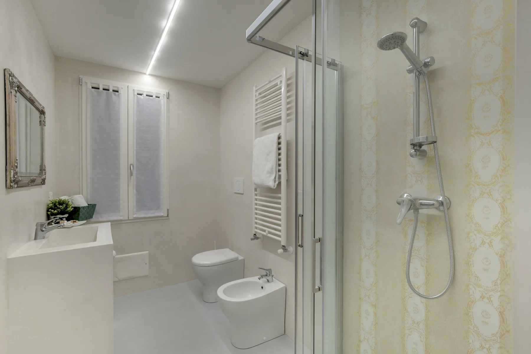 A bright bathroom with a glass shower, sink, and toilet.