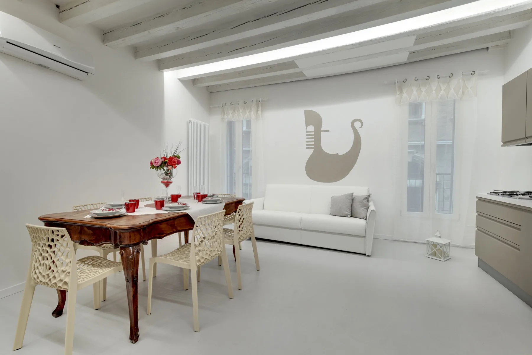 A bright dining and living area with a wooden table and white seating.