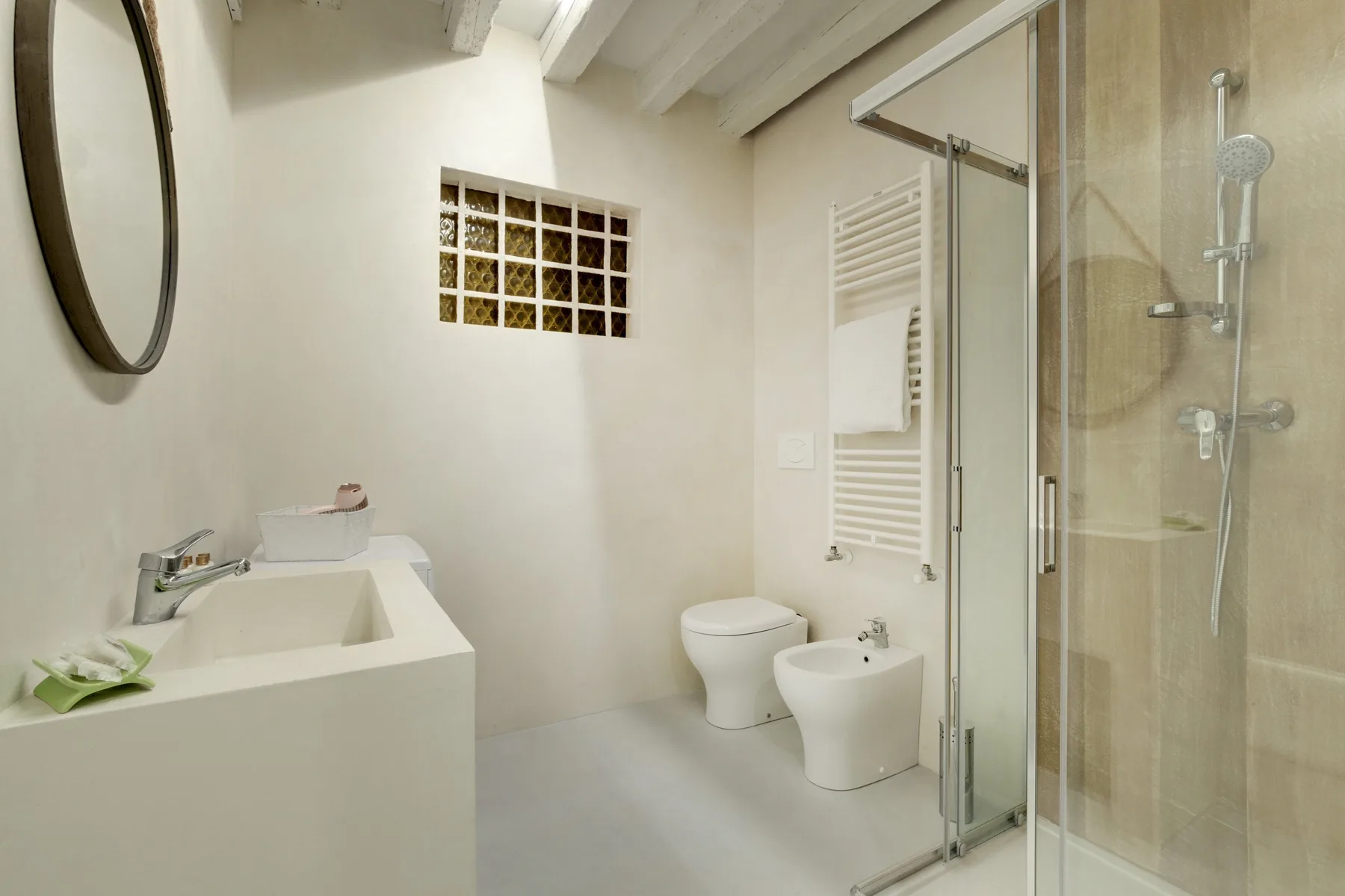A bright bathroom with a sink, toilet, bidet, and glass shower.