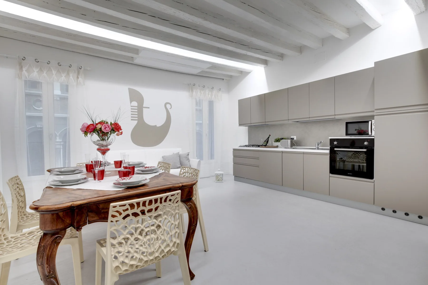 A bright dining area and kitchen with a set dining table and wall cabinets.