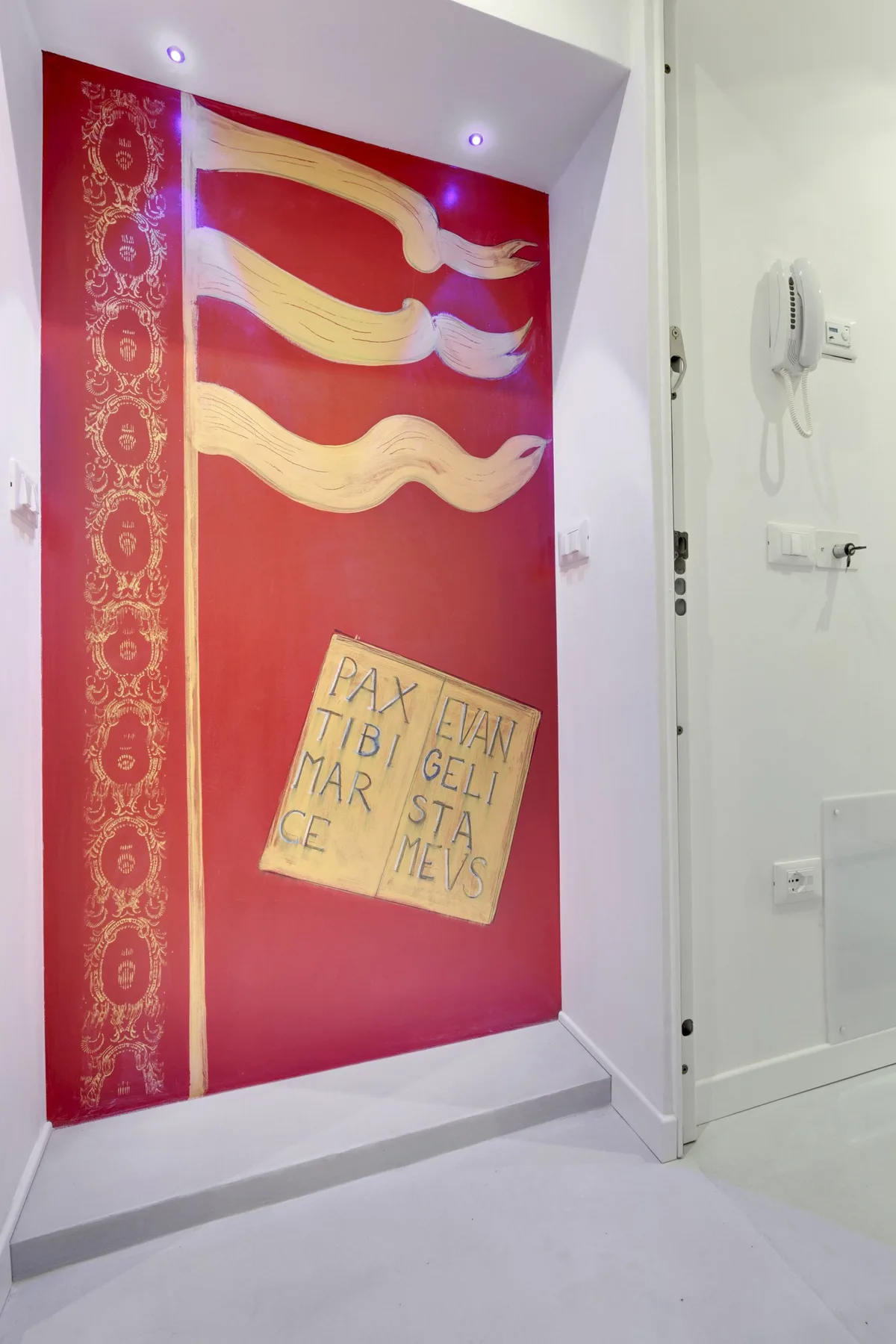 A red decorative wall panel with gold patterns and a small handwritten sign.