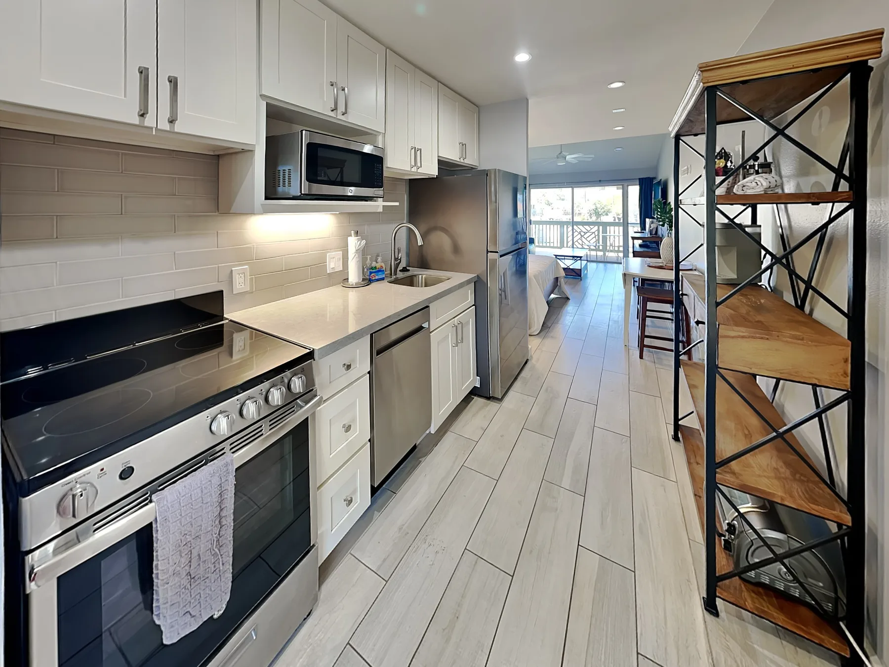 A narrow kitchen with white cabinets and a stainless-steel range.