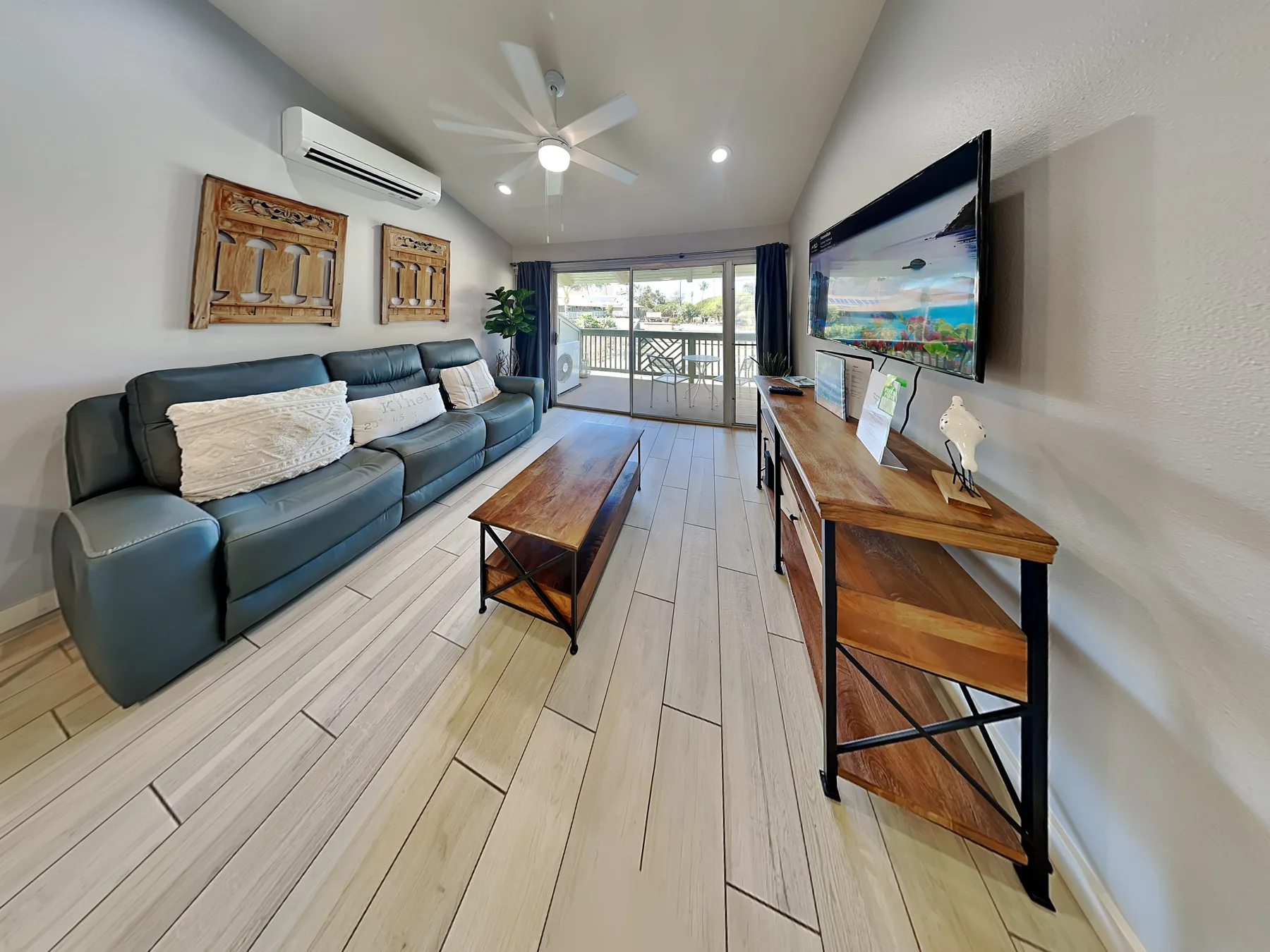 A living room with a sofa, television, and sliding glass doors opening to a balcony.